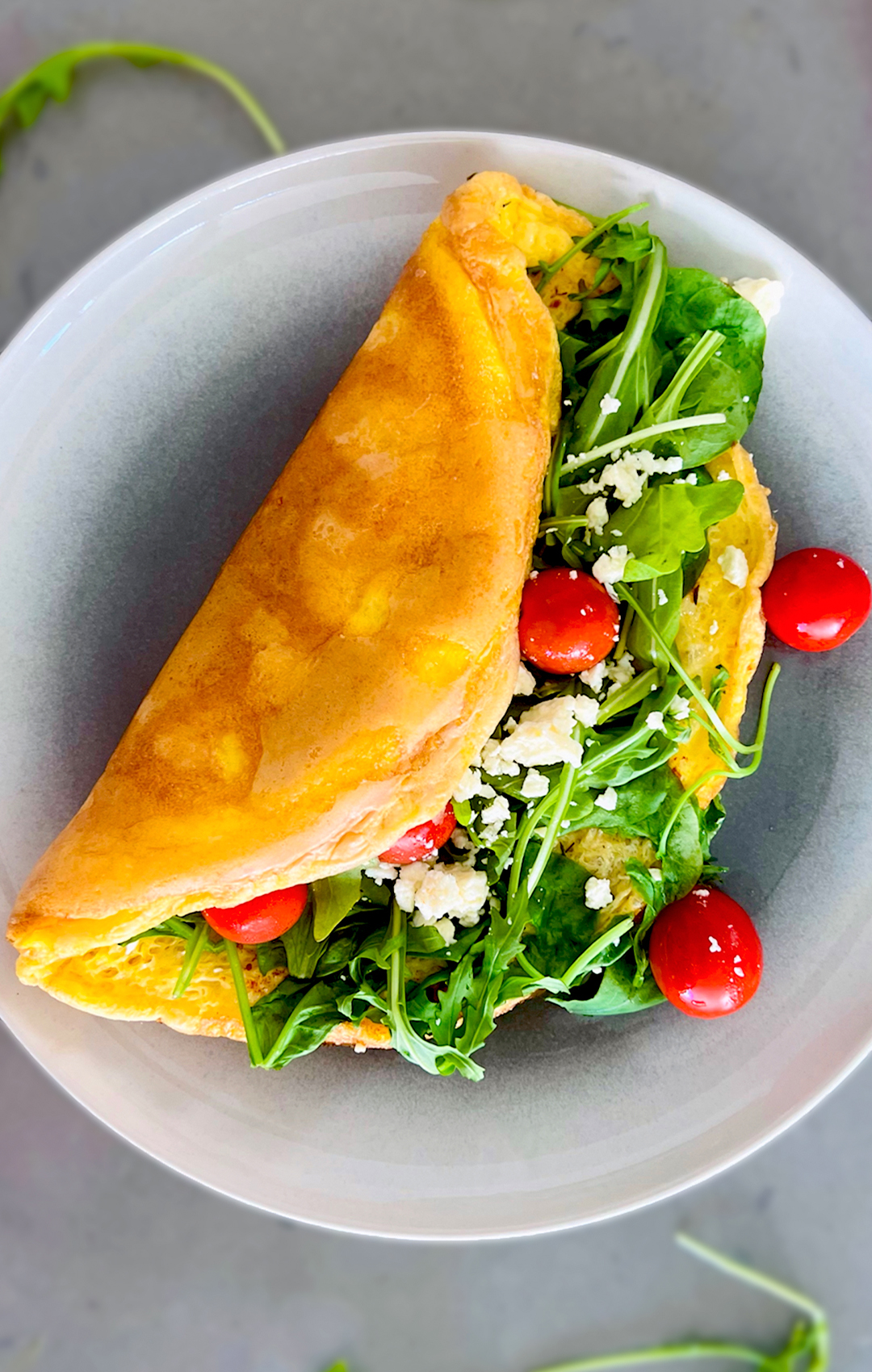 golden crispy fluffy omelette with spinach, arugula, and feta