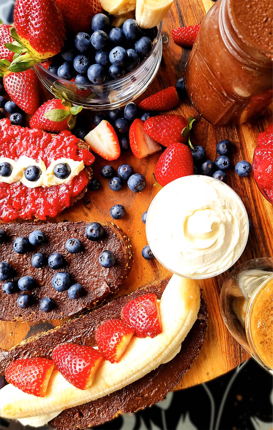 Thick, Healthy Homemade Choco-Nuts Butter generously spread over two slices of dark bread — one topped with blueberries, the other with strawberries and banana. Served with a warm cup of coffee and a bowl of fresh berries. A wholesome, vegan, paleo-friendly treat, free from dairy and refined sugar healthy Nutella recipe