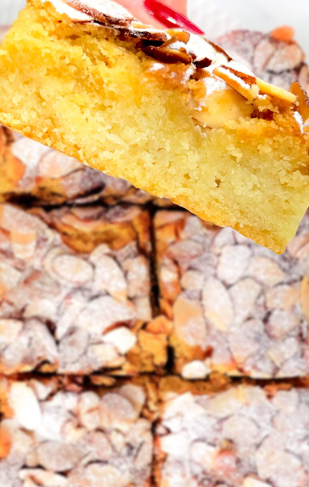 One Almond Croissant Bar held between fingers, showing the soft interior and crunchy almond topping in full detail. Sugar-Free, Paleo, Gluten-free dessert bar.