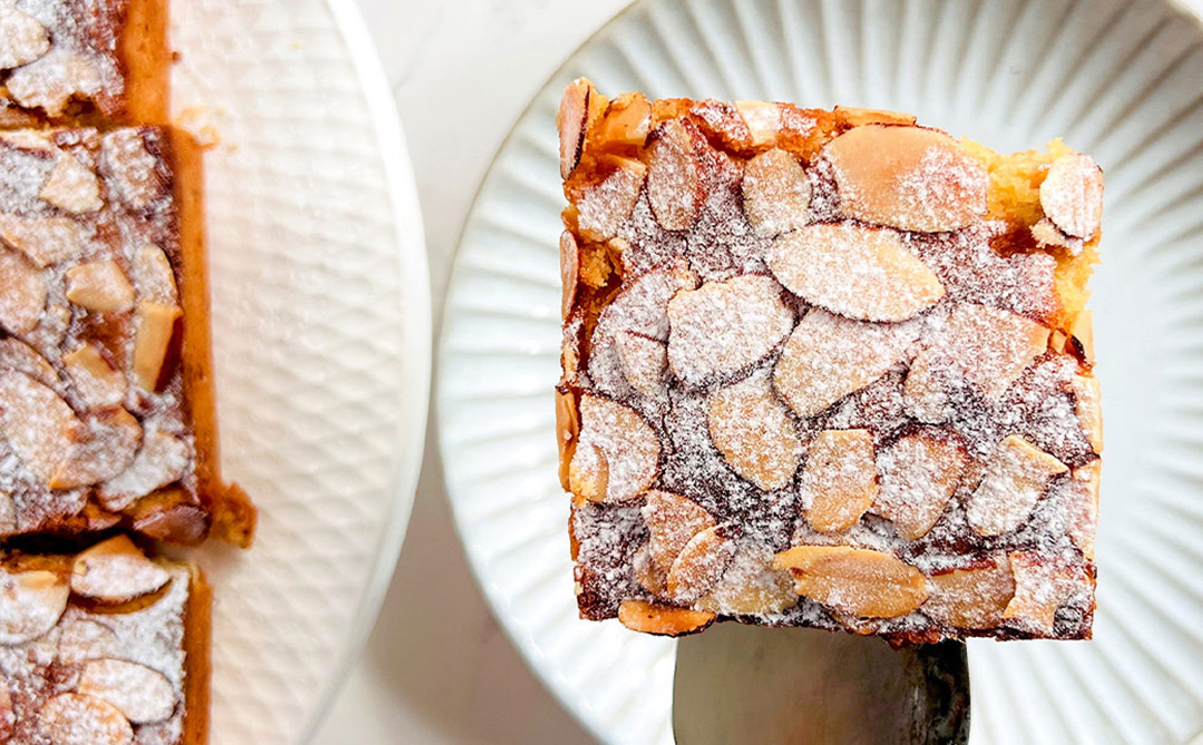 One sliced Almond Croissant Bar served on a plate, showing the glossy almond topping and soft, moist almond centre. Perfect for afternoon gatherings, sugar-free, paleo and grain-free.