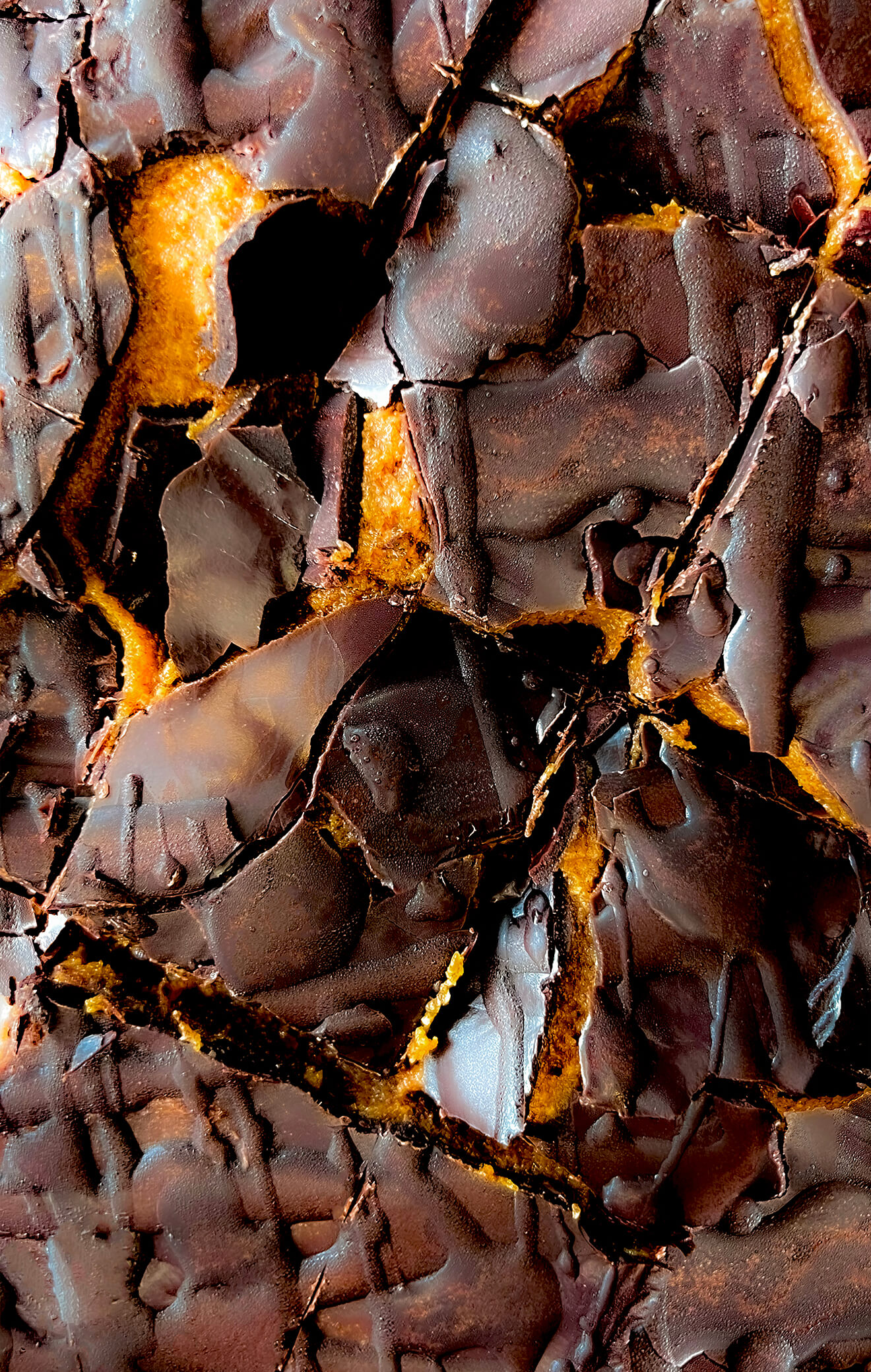 Side angle of a no bake vegan, paleo chocolate bar with a visible crunchy shell and soft rich creamy caramel layer inside