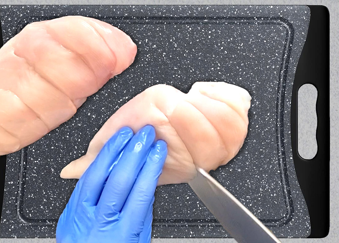 Knife cutting angled slits into the top of a raw chicken breast Image Name: cutting-angled-slits-into-chicken.jpg 