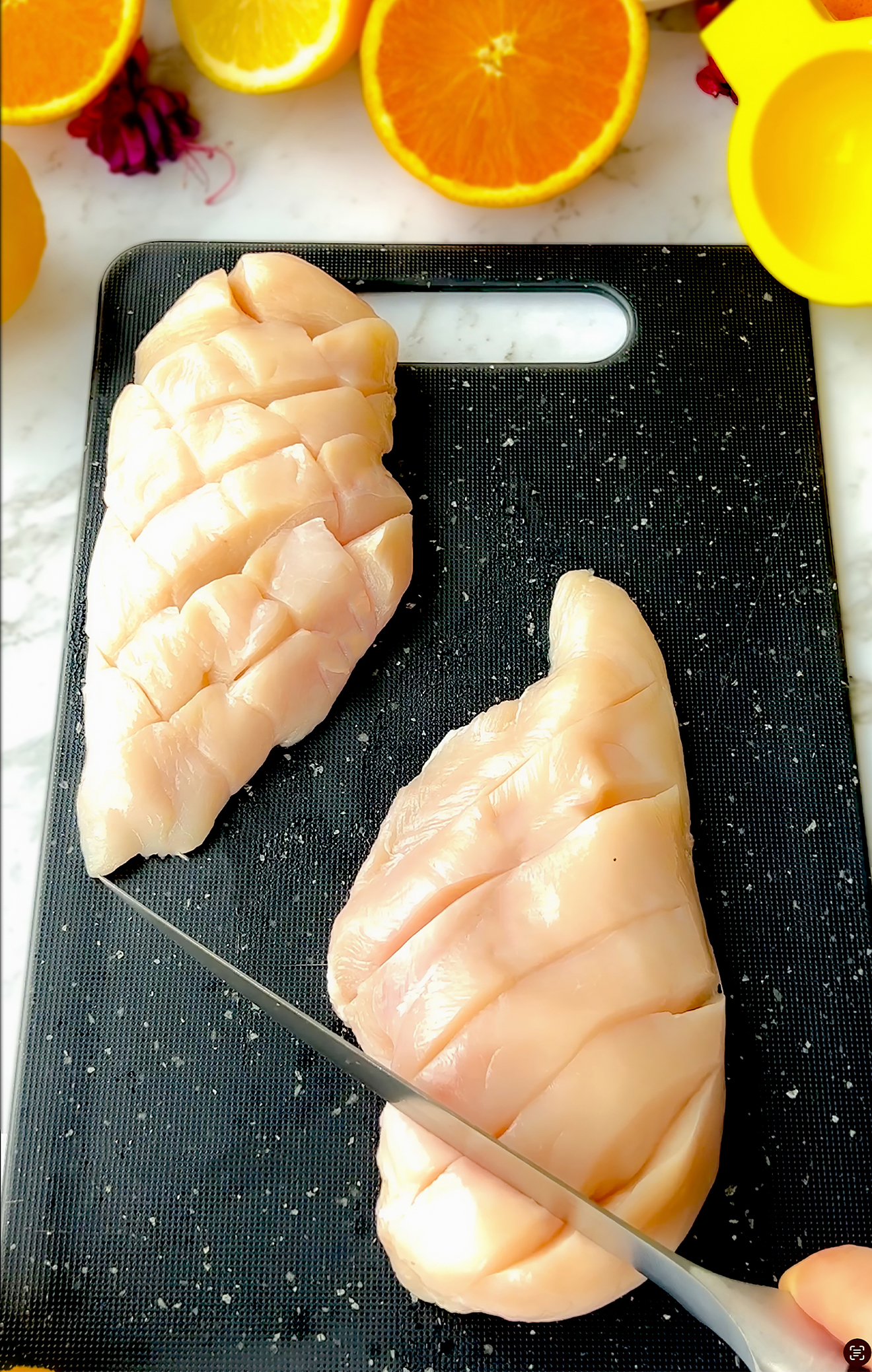 Knife slicing across chicken breast to create full diamond pattern