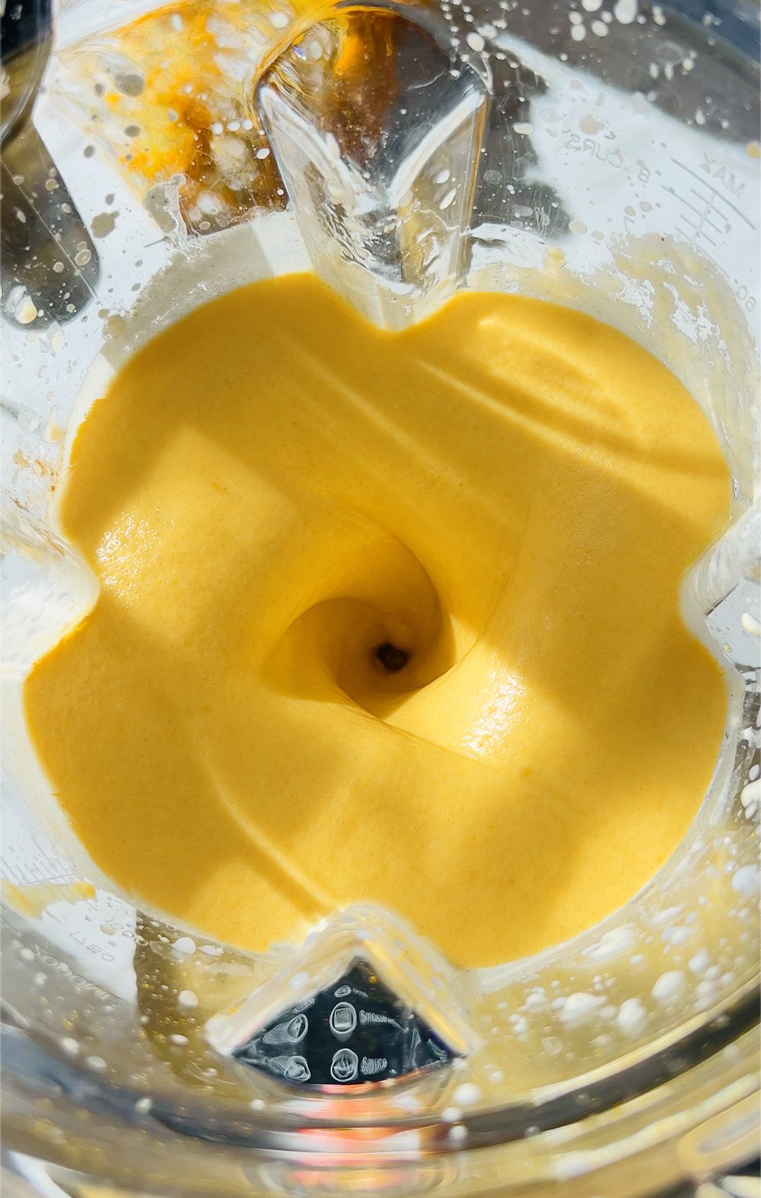 Top view of creamy golden glow smoothie in a blender with beautiful swirl , showing thick, creamy texture and antioxidant-rich blend. Made with cauliflower, Greek yogurt, turmeric powder, Apple, ginger, almond milk, and tahini, honey, pumpkin spice.