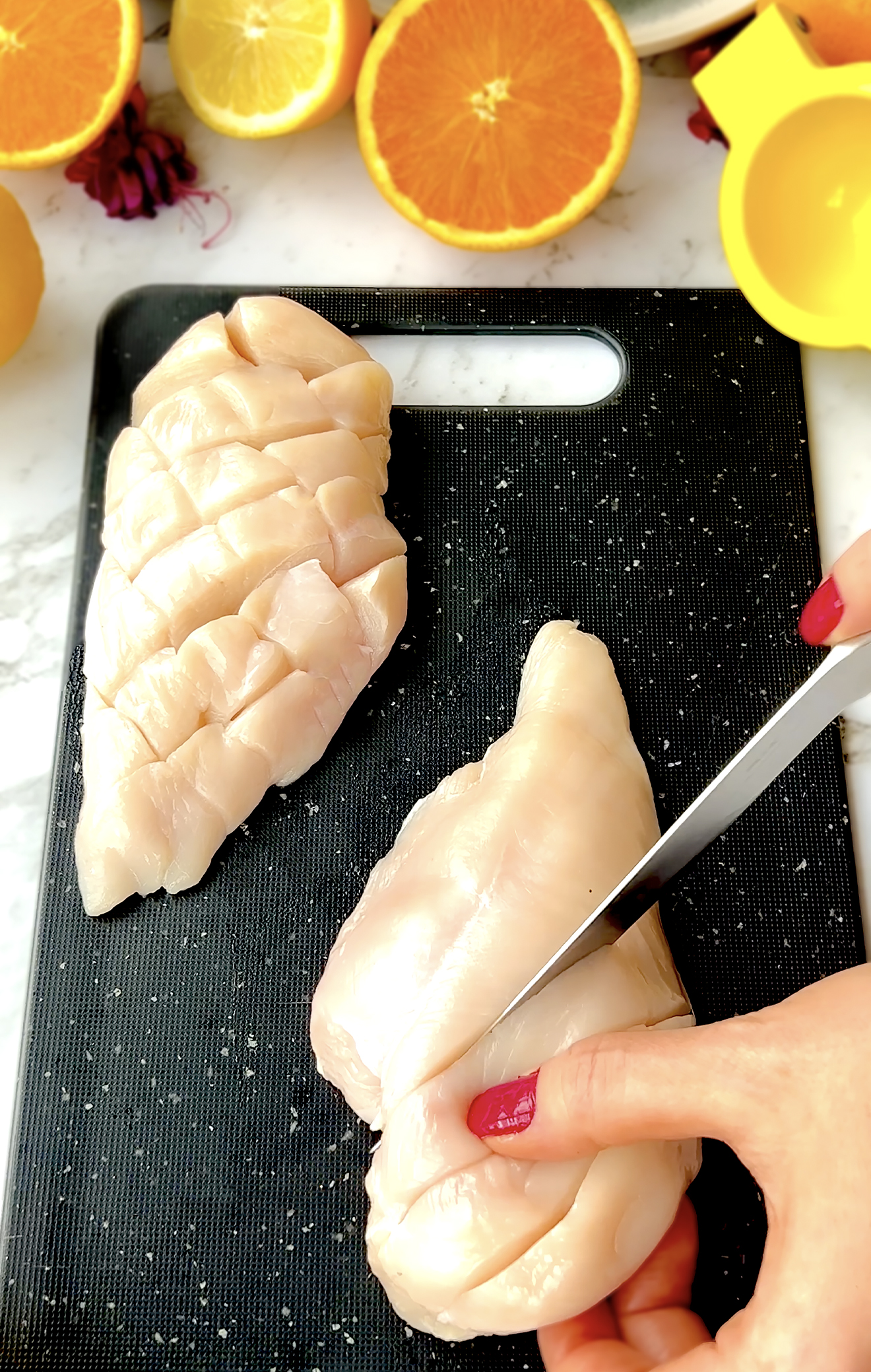 Knife cutting diagonal lines into top of raw chicken breast