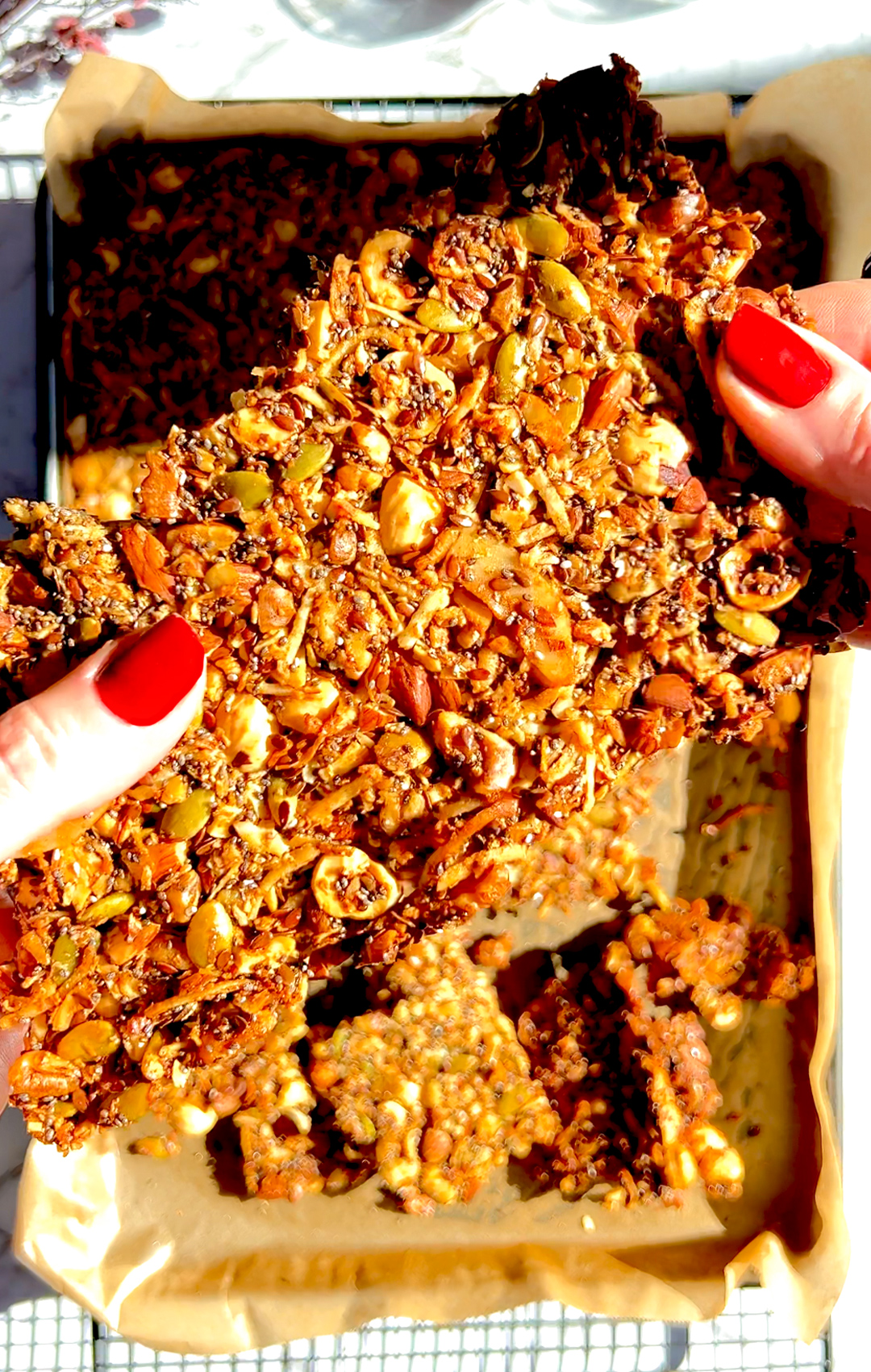 Breaking a big pice of golden Nutty Coconut Crunch Granola by hand. This superfood Made with hazelnuts, almonds, walnuts, egg white, chia seeds, pumpkin seeds, shredded coconut, and flaxseeds.it is paleo, keto, grain-free, high-protein.