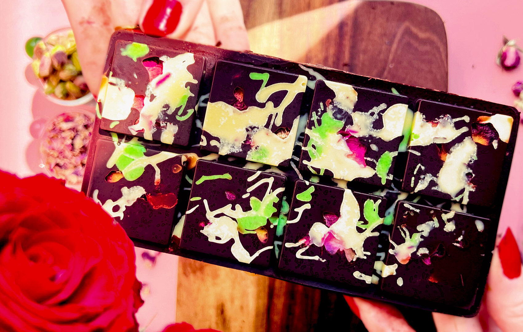 Segmented Healthy Dubai Chocolate Bar with a glossy dark chocolate shell decorated with rose petals and white-green drizzle. Inside, a creamy pistachio-tahini paste with toasted coconut adds crunch. Smooth, creamy, gooey, and crunchy all in one bite. Healthy, refined sugar free, gluten free, keto and paleo option.
