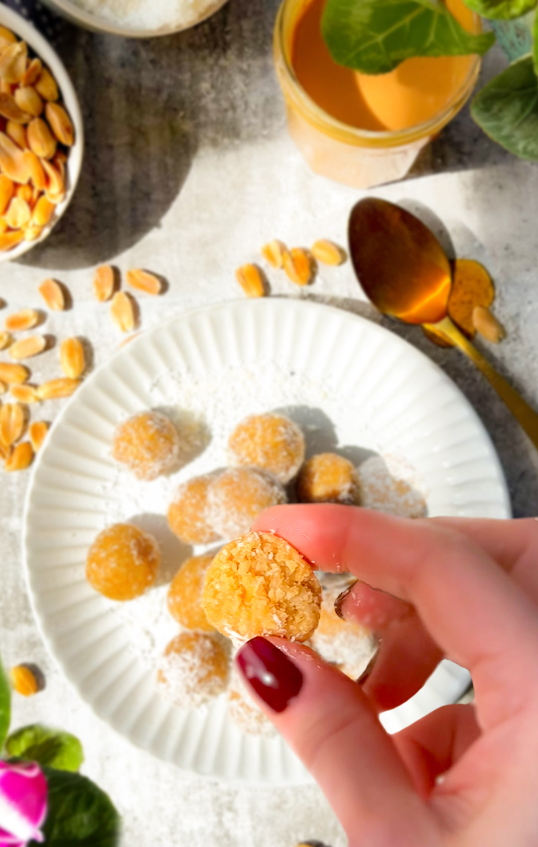 Hand holding a bitten peanut butter coconut energy ball showing soft chewy inside. High protein, low carb, paleo and keto friendly energy snack.