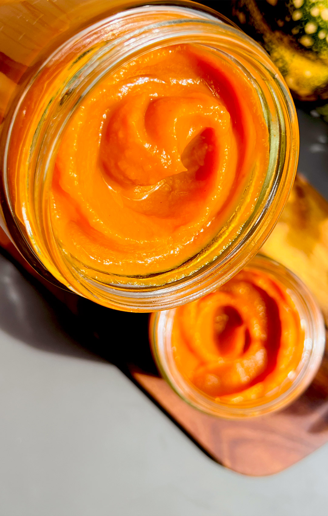 Close up of silky, creamy homemade pumpkin purée in glass jars and shows Thick & Creamy, No Water. Perfect for pies, cheesecakes, pancakes, and healthy fall desserts.