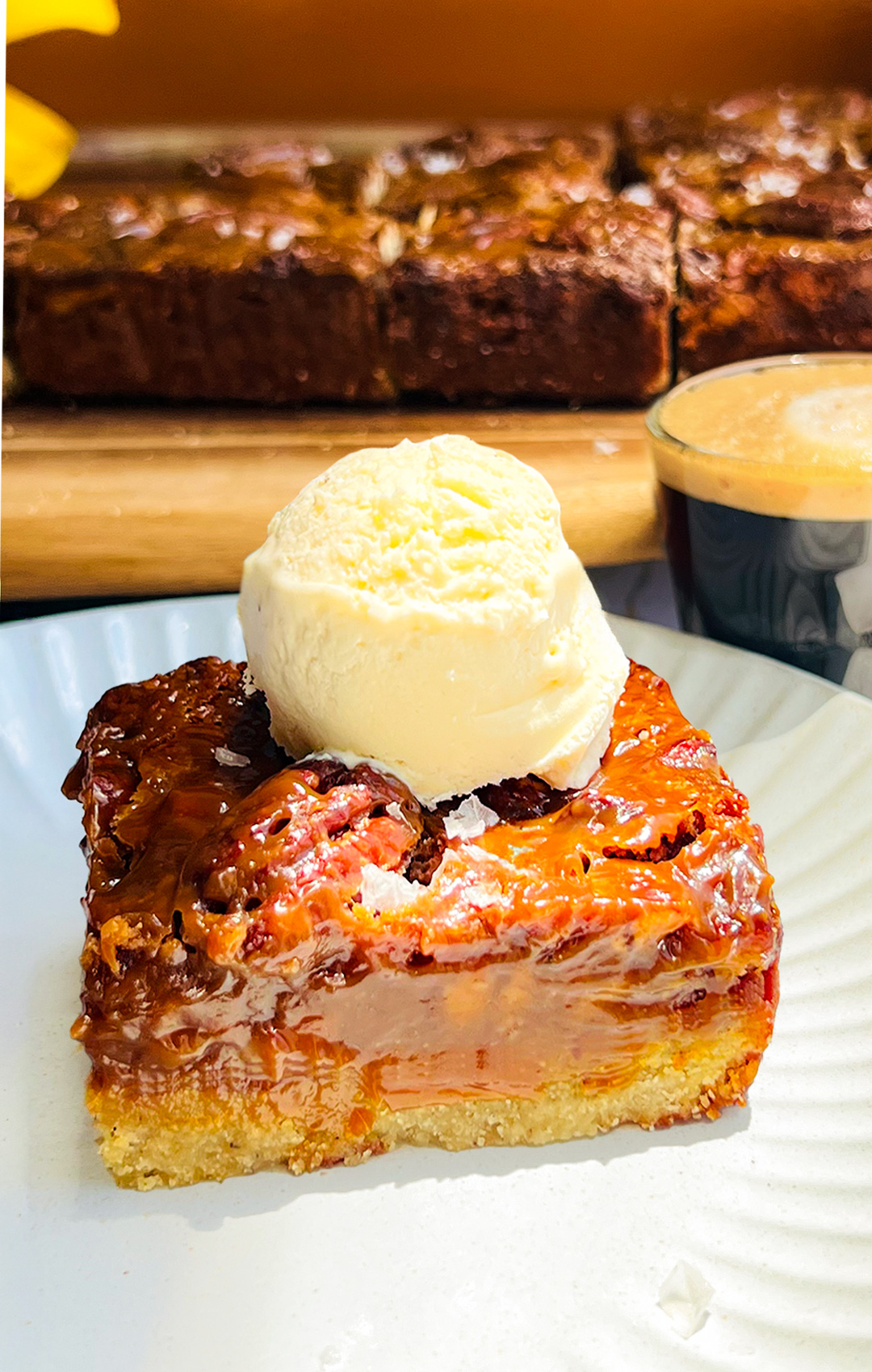 Healthy caramel pecan pie bar on a plate topped with creamy vanilla ice cream and flaky sea salt, showing gooey chewy maple caramel pecan layer that made of maple syrup and brown monk fruit and almond flour base, paleo, gluten free, refined sugar free dessert, perfect with coffee.for keto option Swap maple syrup for sugar free maple syrup
