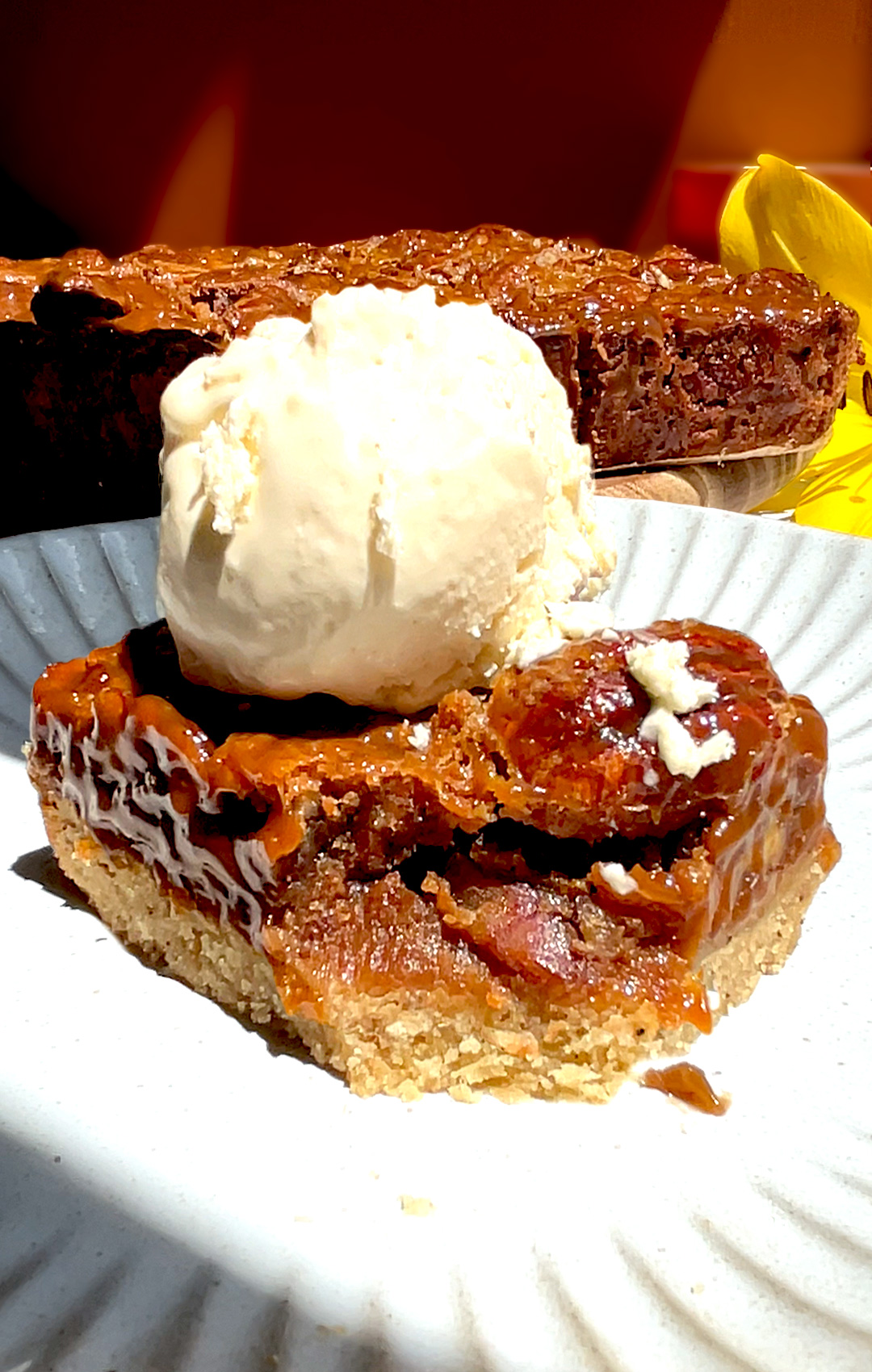 © Healthy Food by Annie – All rights reserved. No reuse without permission. Close up of a healthy caramel pecan pie bar with a forkful taken out, showing the gooey chewy maple caramel pecan layer made with maple syrup and brown monk fruit, packed with toasted pecans on top of a buttery almond flour shortbread base, topped with melting vanilla ice cream and sea salt, paleo, gluten free, grain free, refined sugar free and lower carb dessert. For keto option Swap maple syrup for sugar free maple syrup