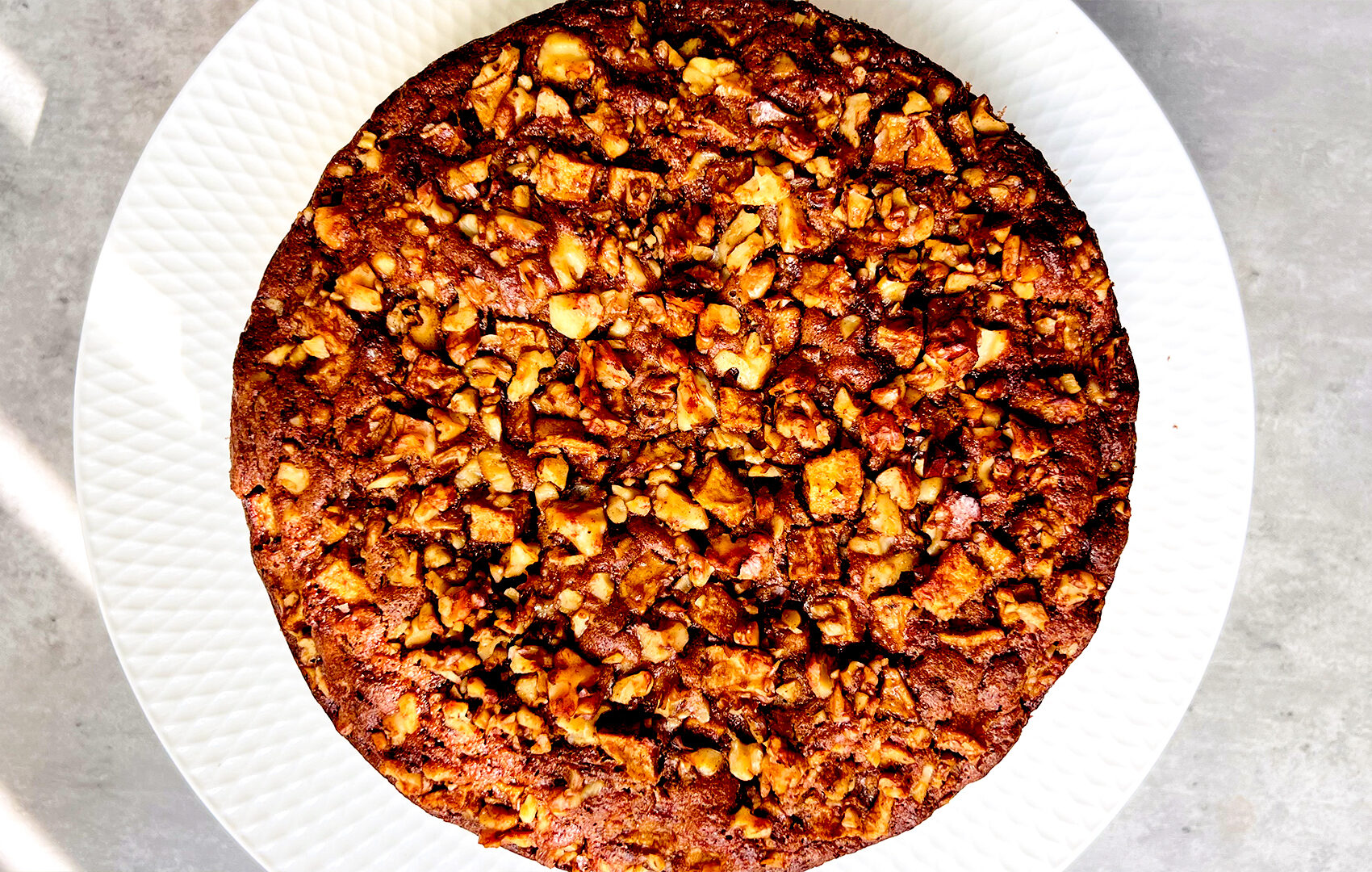 Close-up of apple pudding cake with a caramelised walnut and apple topping, crispy edges and moist almond flour crumb. Naturally sweetened, healthy, gluten-free, dairy-free and paleo-friendly.