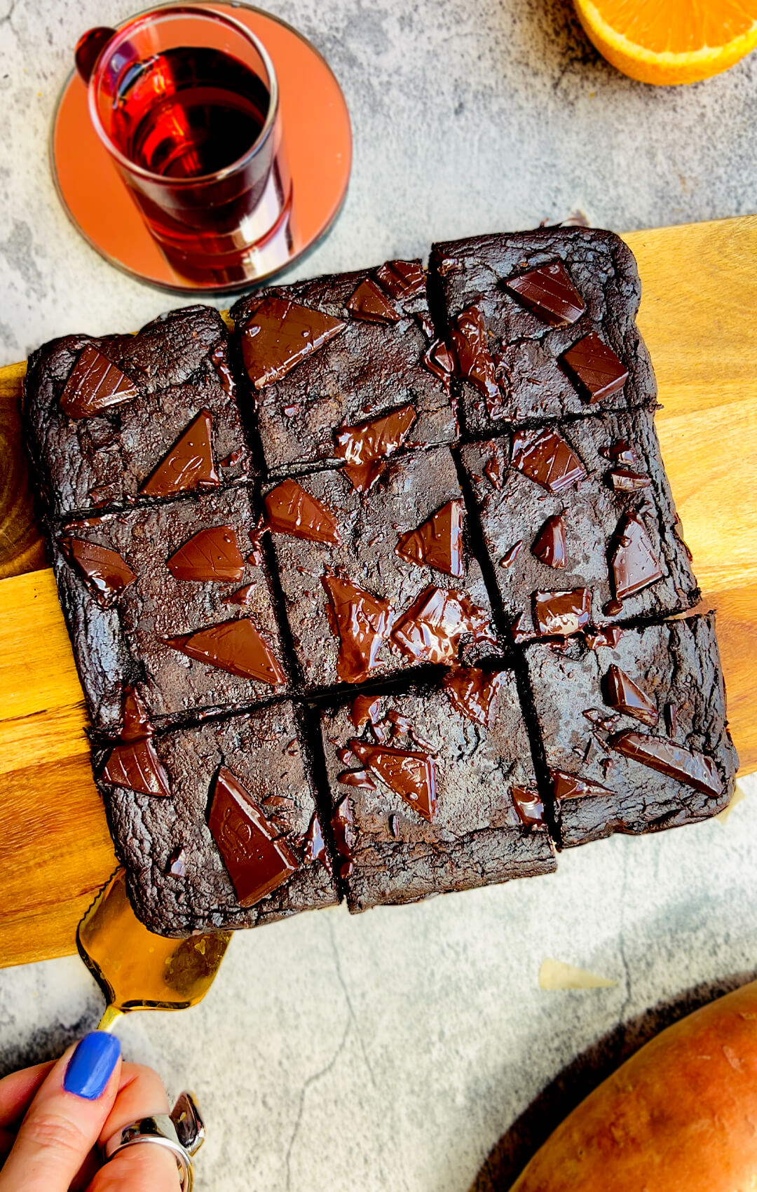 Healthy sweet potato chocolate brownies on a timber board, glossy melted chocolate on top, being lifted with a spatula, one bowl gluten free low carb and no sugar added recipe treat.