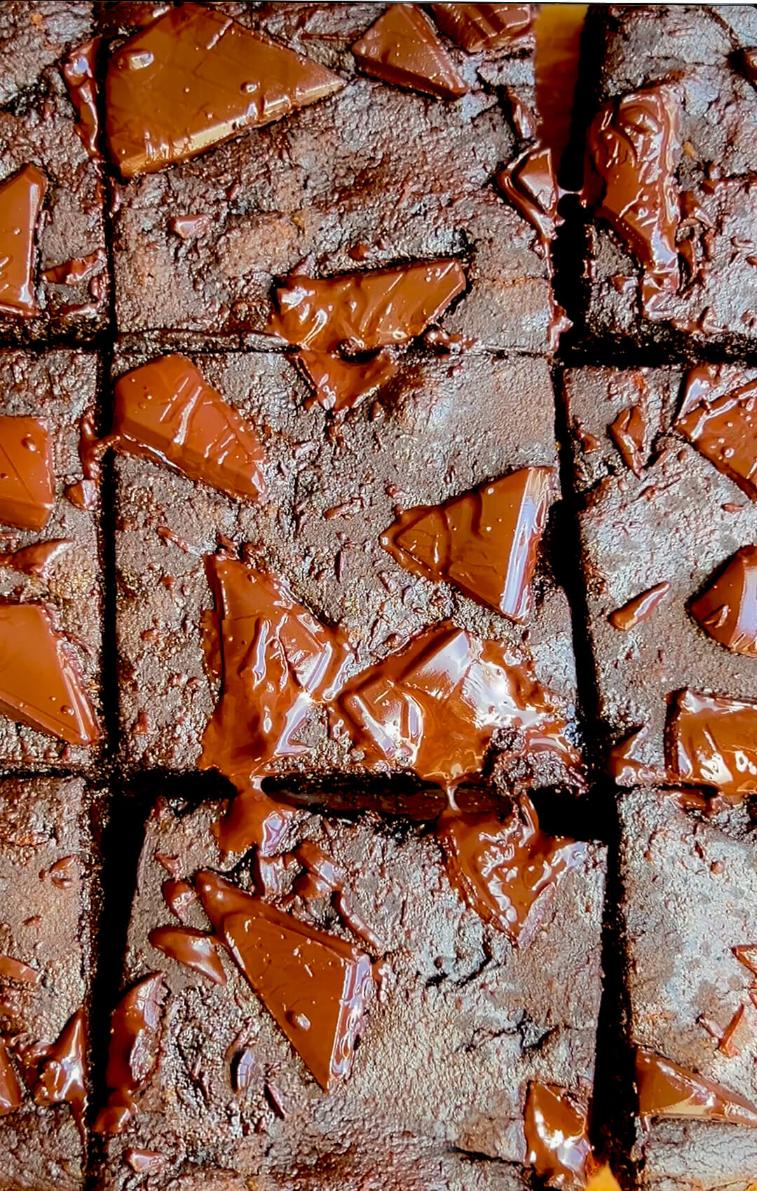 Overhead close up of shiny sweet potato chocolate brownies with shiny melted chocolate chunks, healthy one bowl brownie recipe that is flourless, gluten free, no sugar added, low-carb, paleo, and nut free.