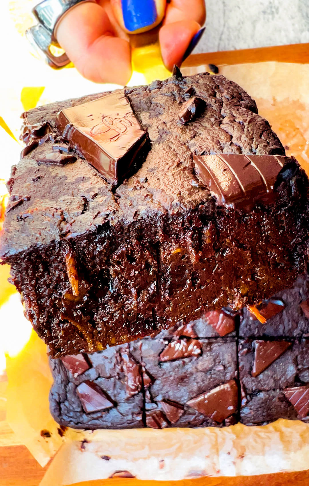 Close up of a Thick square of fudgy sweet potato brownie on a spatula, rich chocolate crumb, gooey inside, healthy flourless gluten free brownie with no added sugar, paleo