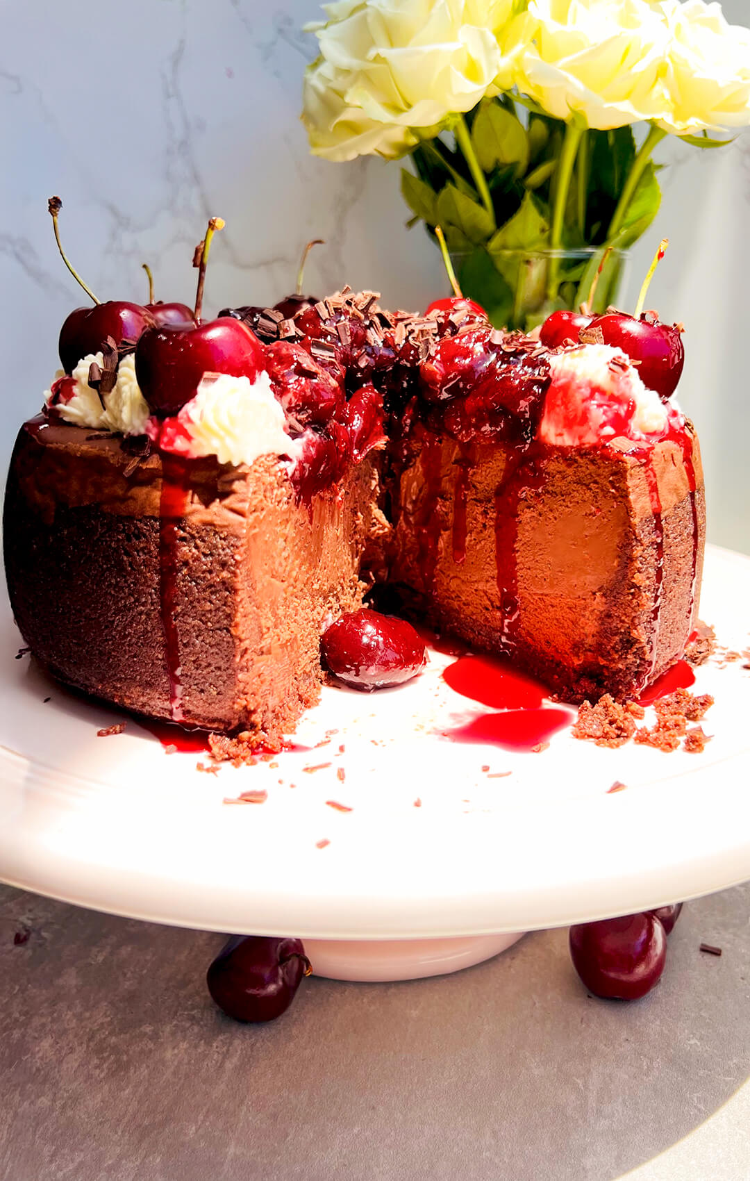 Best sugar-free Black Forest cheesecake cut open to reveal a tall, clean chocolate cheesecake with a silky interior, crunchy chocolate crust, and glossy homemade cherry topping made with monkfruit, drivelling cherry sauce