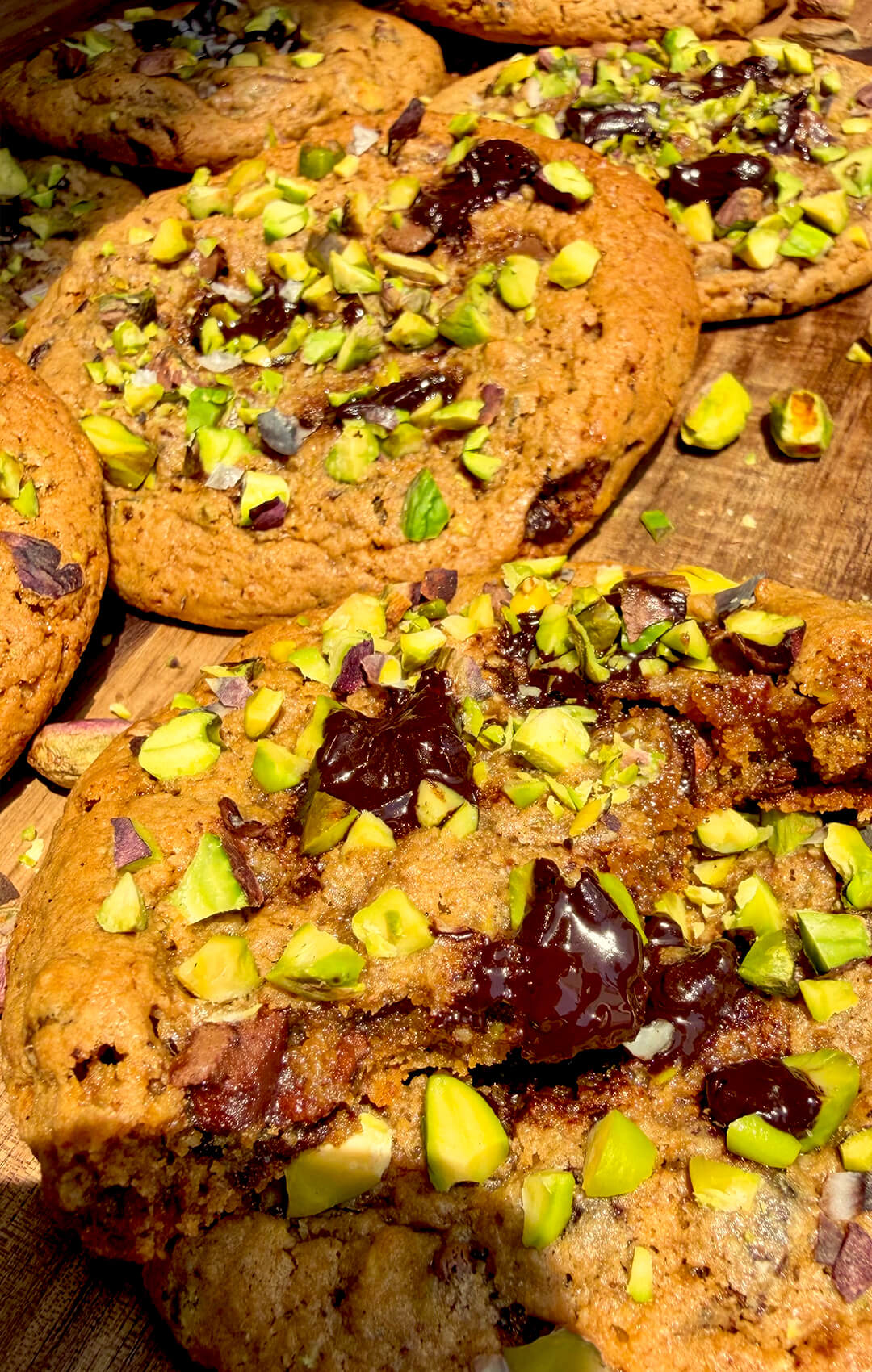 Extreme close-up of soft chewy pistachio cookie interior with melted dark chocolate and caramelised golden crumb, gluten-free almond flour cookie.