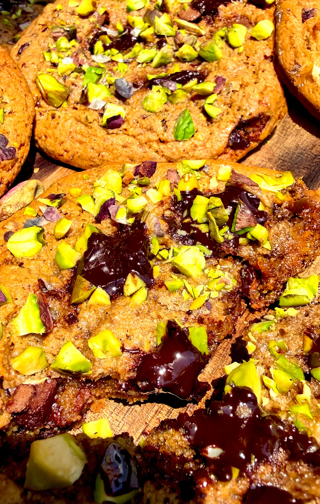 Extreme close-up of soft chewy pistachio cookie interior with melted dark chocolate and caramelised golden crumb, gluten-free almond flour cookie.