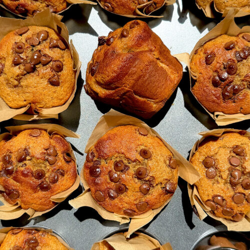Overhead platter of Banana Oat Chocolate Chip Muffins with cinnamon sticks, golden tops and chocolate chips, quick and easy high protein high fiber muffins made with oat flour and lupin flour.