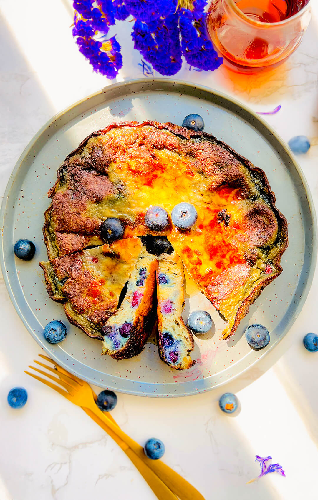 Fluffy blueberry omelet on a plate, golden and puffy with juicy blueberries and golden caramelised edges, Ready in 10 minutes with simple ingredients. flourless, keto, gluten-free, sugar-free healthy, breakfast or brunch, it looks like a café-style breakfast on a plate.