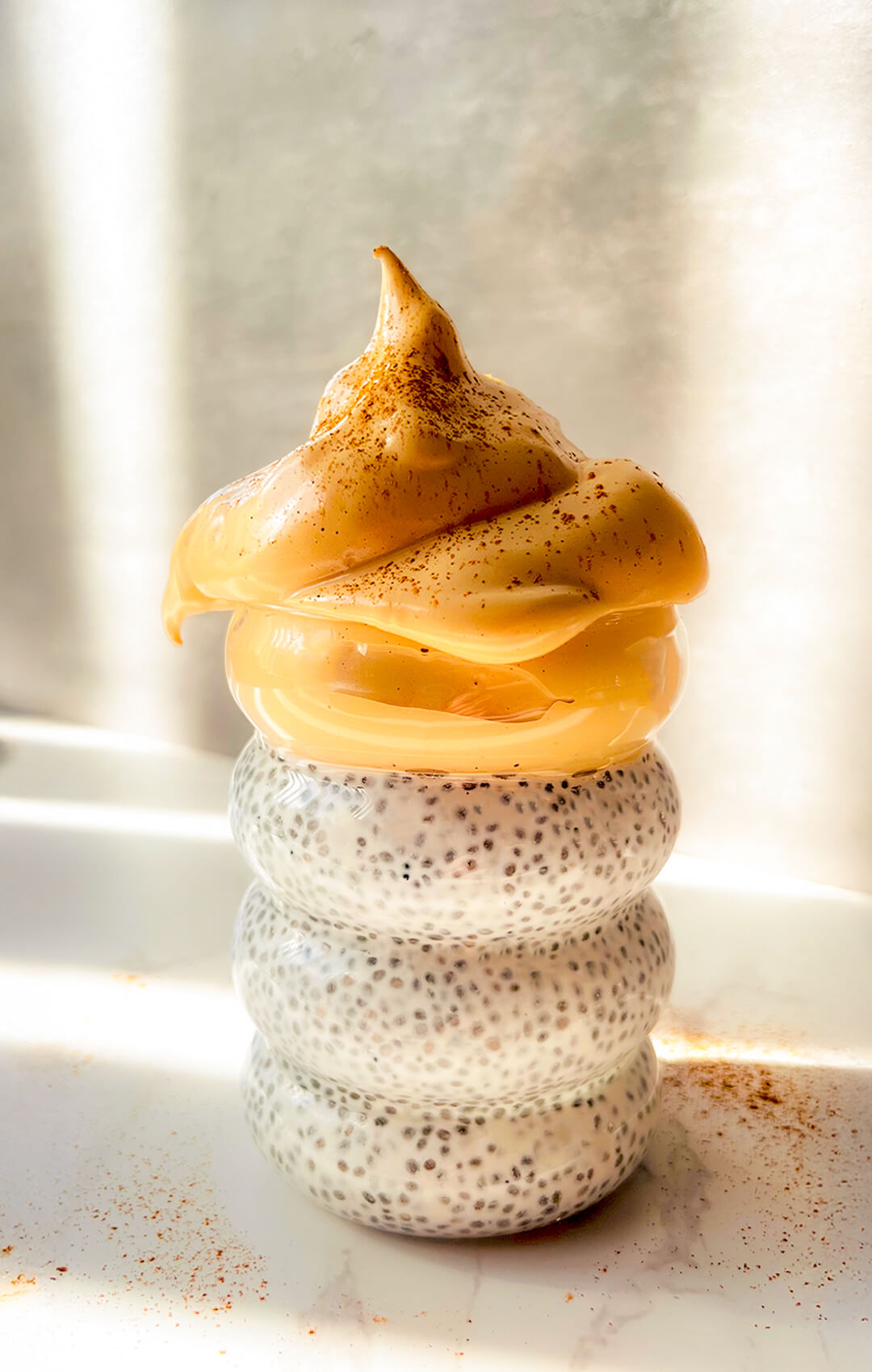 Honey Dalgona Coffee Chia Pudding in a glass with creamy vanilla chia pudding and a thick velvety whipped honey coffee topping, dusted with cinnamon, a healthy mix of morning coffee and breakfast that is paleo, gluten-free, dairy-free, refined sugar-free, quick and easy to make in 5 minutes, and perfect for breakfast or an afternoon treat.