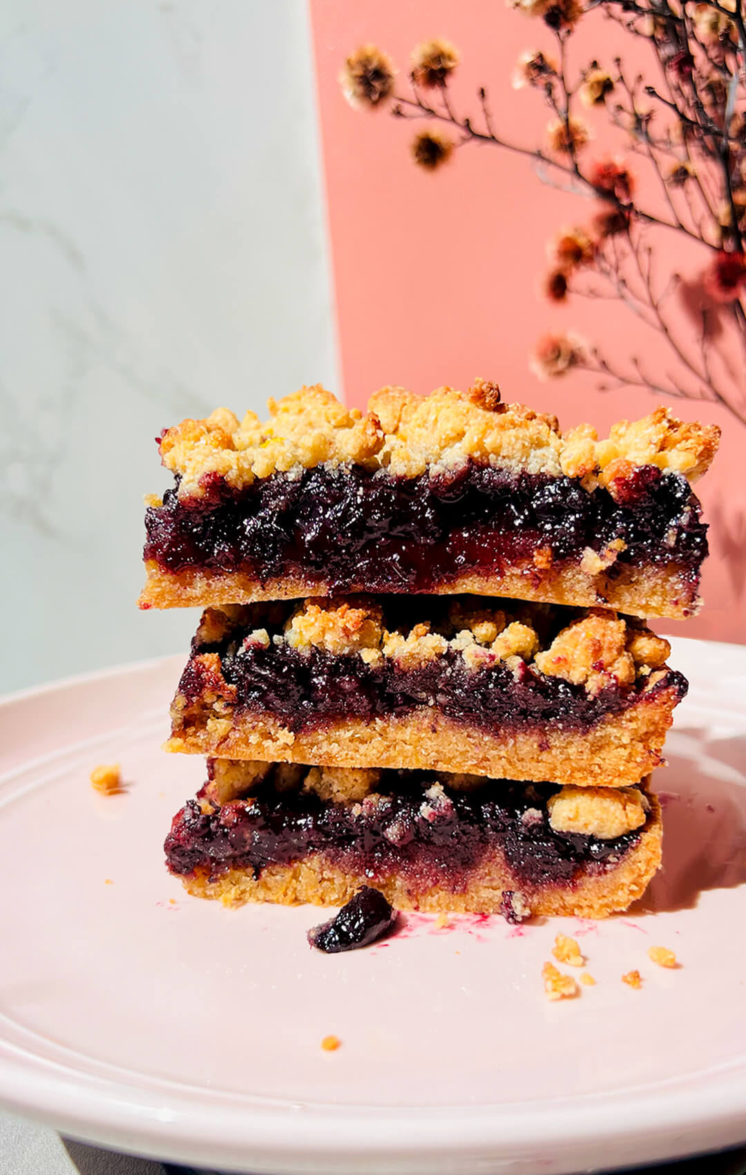 Stacked healthy blueberry crumble bars showing the rich jammy and shiny blueberry sauce layer with whole berries and a tender buttery base under a golden crumble topping, gluten-free, grain-free, dairy-free and paleo friendly with vegan option. made with almond flour, coconut flour, coconut sugar, coconut oil and lemon zest.