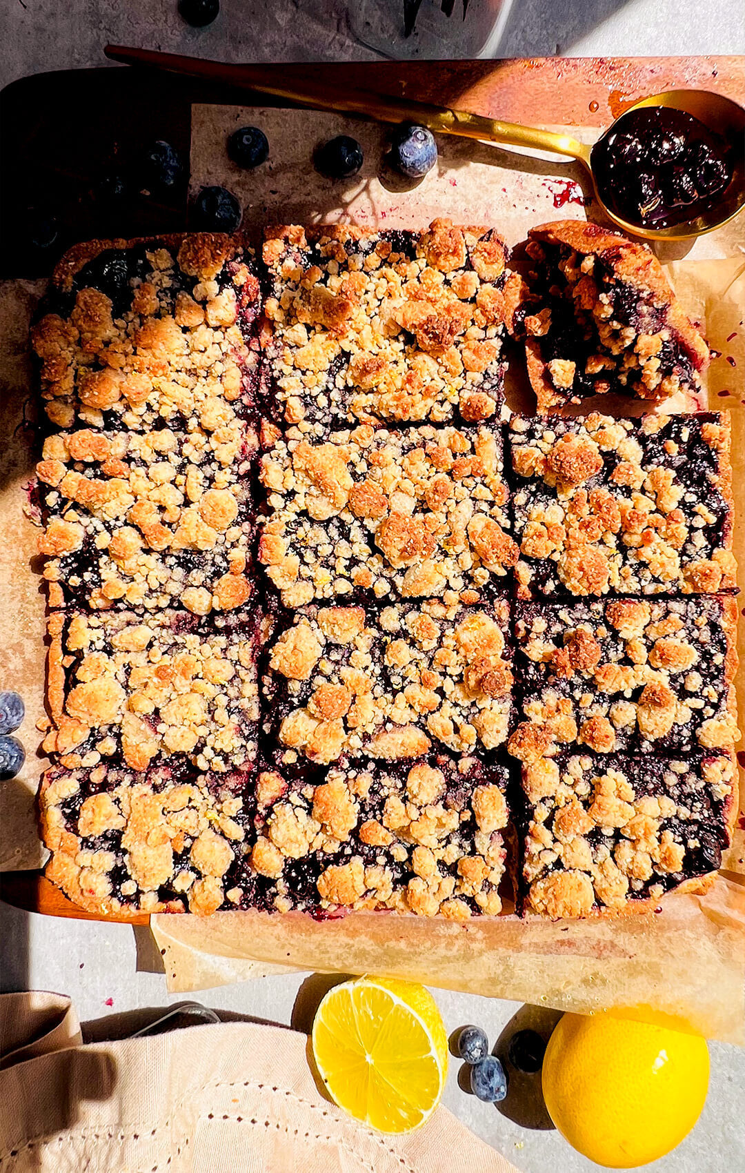Top view of a full tray of healthy gluten-freeblueberry crumble bars with a golden buttery crumble topping and jammy blueberry filling sweet, tangy, glossy, and full of blueberry flavour, a make-ahead gluten-free, paleo, refined sugar-free and dairy-free snack or dessert that stores well in the fridge for meal prep. made with almond flour, coconut flour and coconut oil and homemade blueberry sauce.
