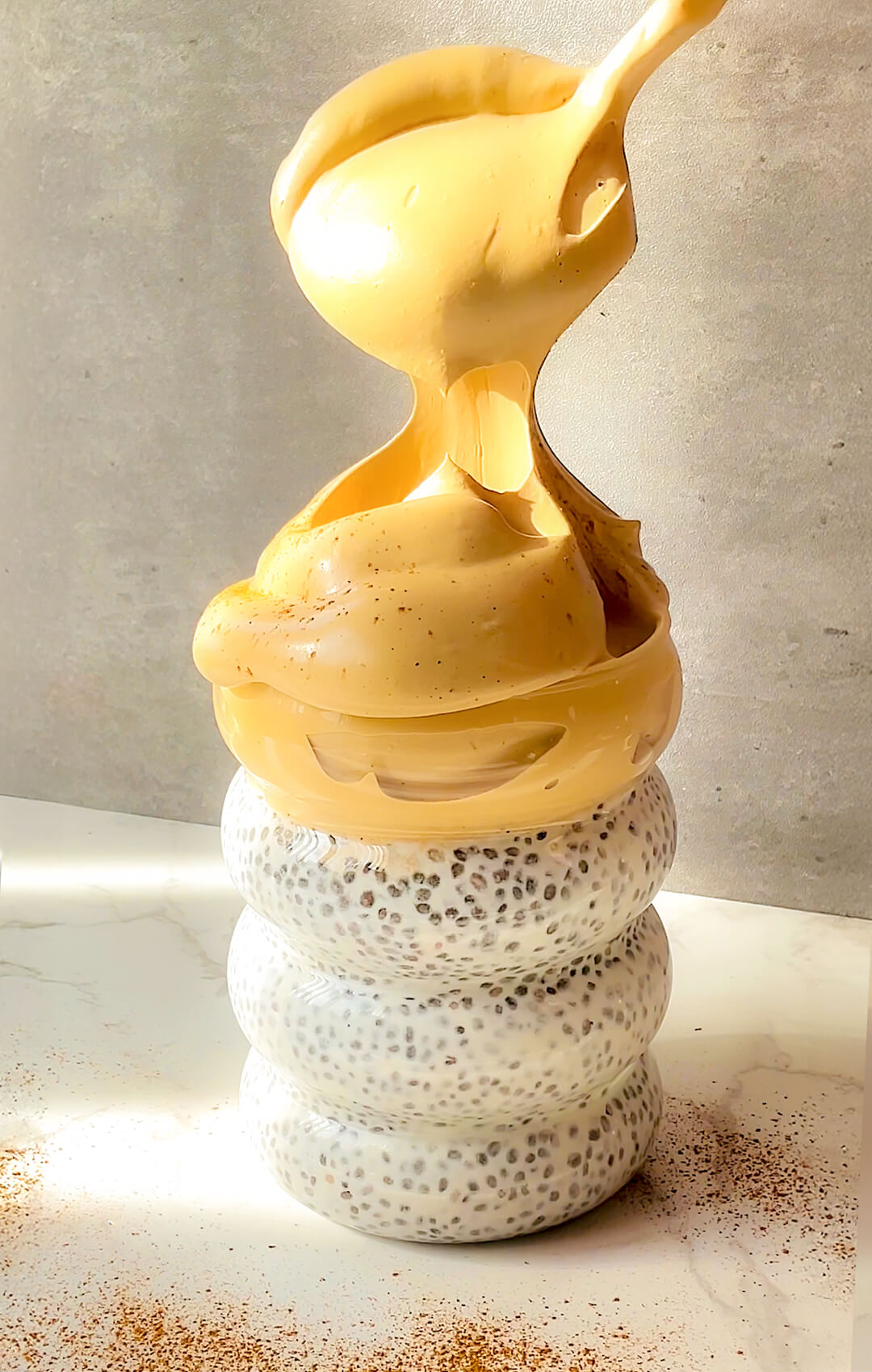 Creamy Honey Dalgona Coffee Chia Pudding with silky whipped honey coffee being spooned over vanilla chia pudding, showing the luscious cloud-like texture that holds its shape beautifully, a healthy breakfast and morning coffee in one, paleo, gluten-free, dairy-free, refined sugar-free, and ready in 5 minutes.