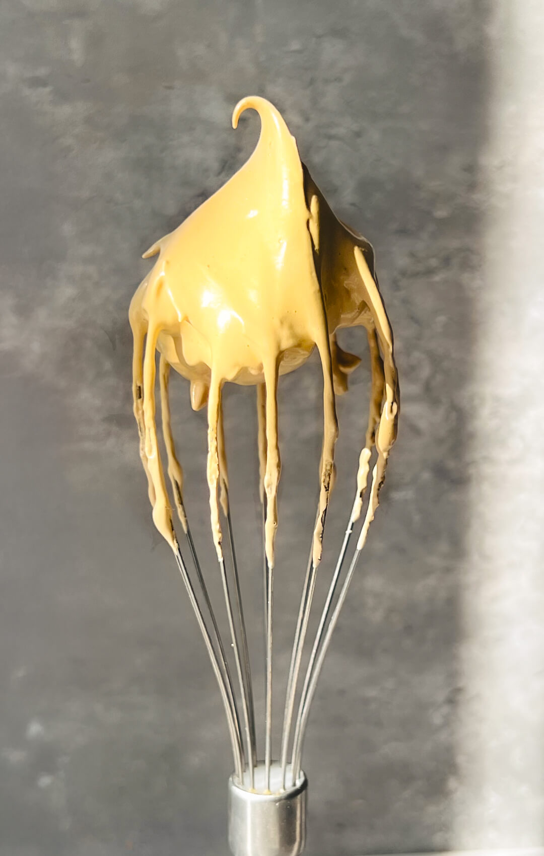 Velvety whipped honey dalgona coffee on a whisk, showing glossy soft peaks and a thick stable texture that holds its shape beautifully, perfect for topping chia pudding and creating a healthy mix of morning coffee and breakfast, quick and easy to make in 5 minutes with simple wholesome ingredients.