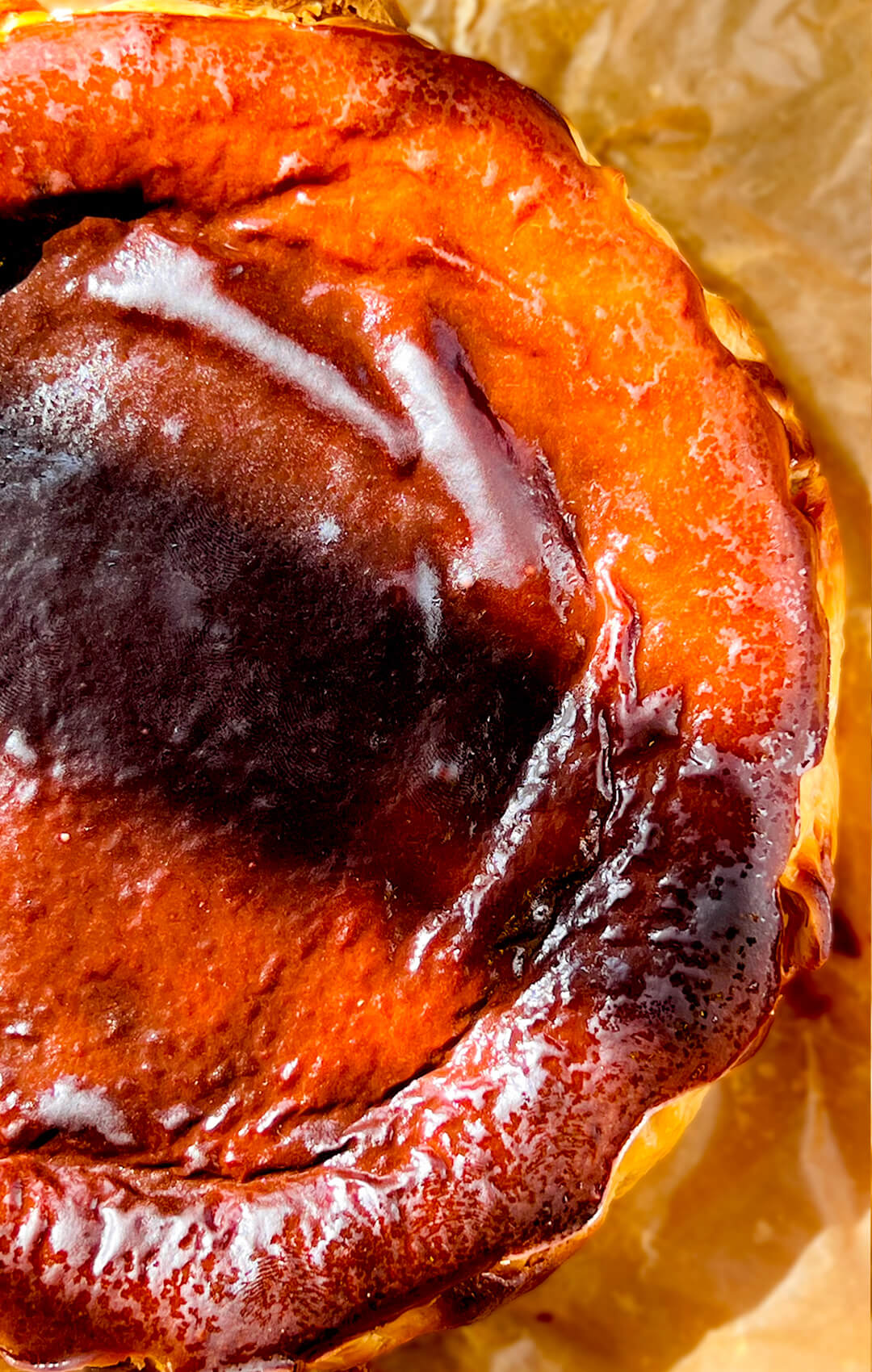 Close-up of a Basque Burnt Cheesecake showing the glossy dark burnt top, golden edges, and rustic baked surface.