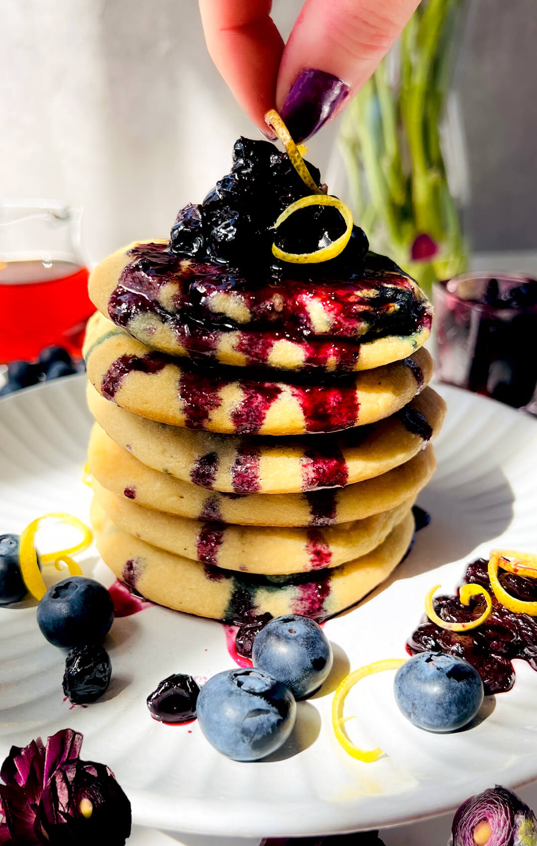 Close-up of thick fluffy paleo blueberry pancakes with blueberry sauce, showing their soft, tender, pillowy texture, juicy blueberries, naturally light sweetness, and cozy brunch look. these pancakes are gluten-free, Dairy-Free, Grain-Free, Refined Sugar-Free, Vegetarian.