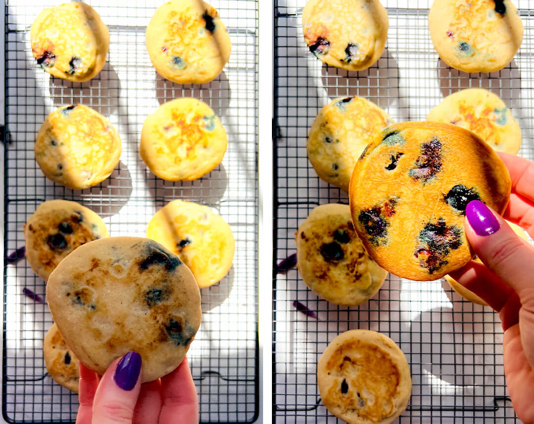 Hand holding a fluffy blueberry pancake over a wire rack, showing the golden surface, soft thick texture, juicy blueberries, and an easy gluten-free dairy-free grain-free coconut flour pancake for breakfast.