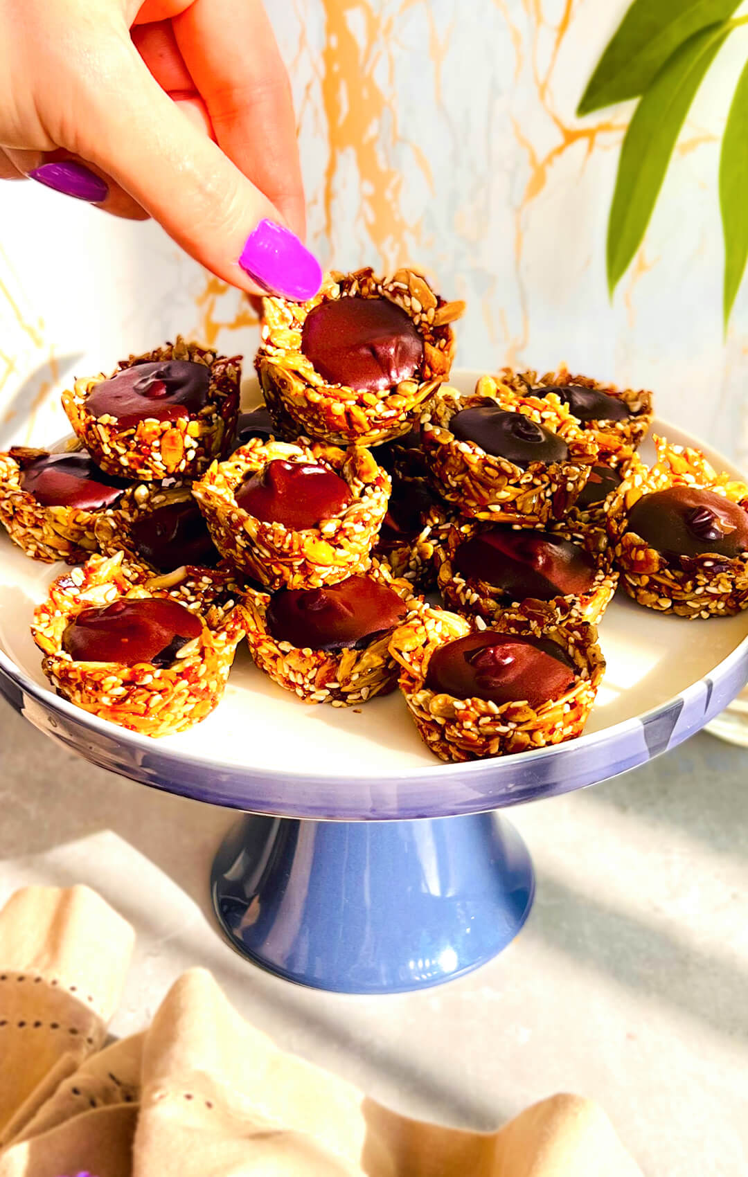 Crunchy No-Oven Chocolate Tahini Seed Cups served on a cake stand, with golden toasted seed cups and a silky, glossy dark chocolate tahini centre. These healthy homemade chocolate seed cups are easy to make without an oven, paleo, gluten-free, nut-free, dairy-free, oil-free, refined sugar-free, delicious, satisfying, and perfect for afternoon tea, lunch boxes, or a wholesome chocolate treat.