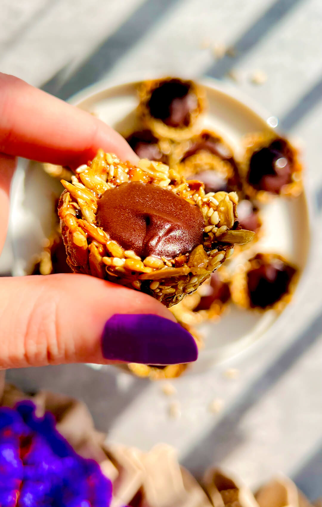 Close-up of a No-Oven Chocolate Tahini Seed Cup with a crunchy golden sunflower seed and sesame cup filled with silky, glossy dark chocolate tahini. This healthy chocolate treat is pan-made, gluten-free, nut-free, dairy-free, oil-free, refined sugar-free, paleo-friendly, delicious, rich, and satisfying for a wholesome snack or little chocolate craving.