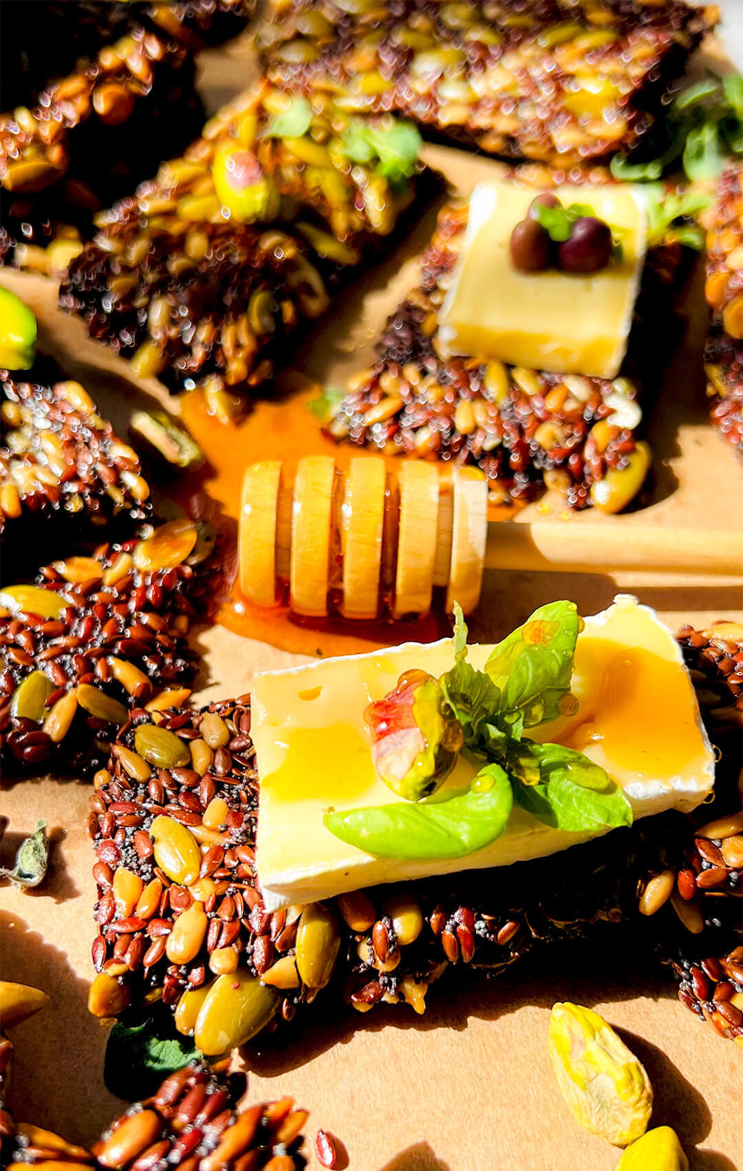 Closeup of crispy, thin Seed crackers served with honey, soft cheese, basil and pistachios, healthy crispy homemade crackers for snacks, dips, cheese boards, salad topping and entertaining. They are Healthy, paleo, keto and vegan. so easy to make at home, no flour and grain-free.