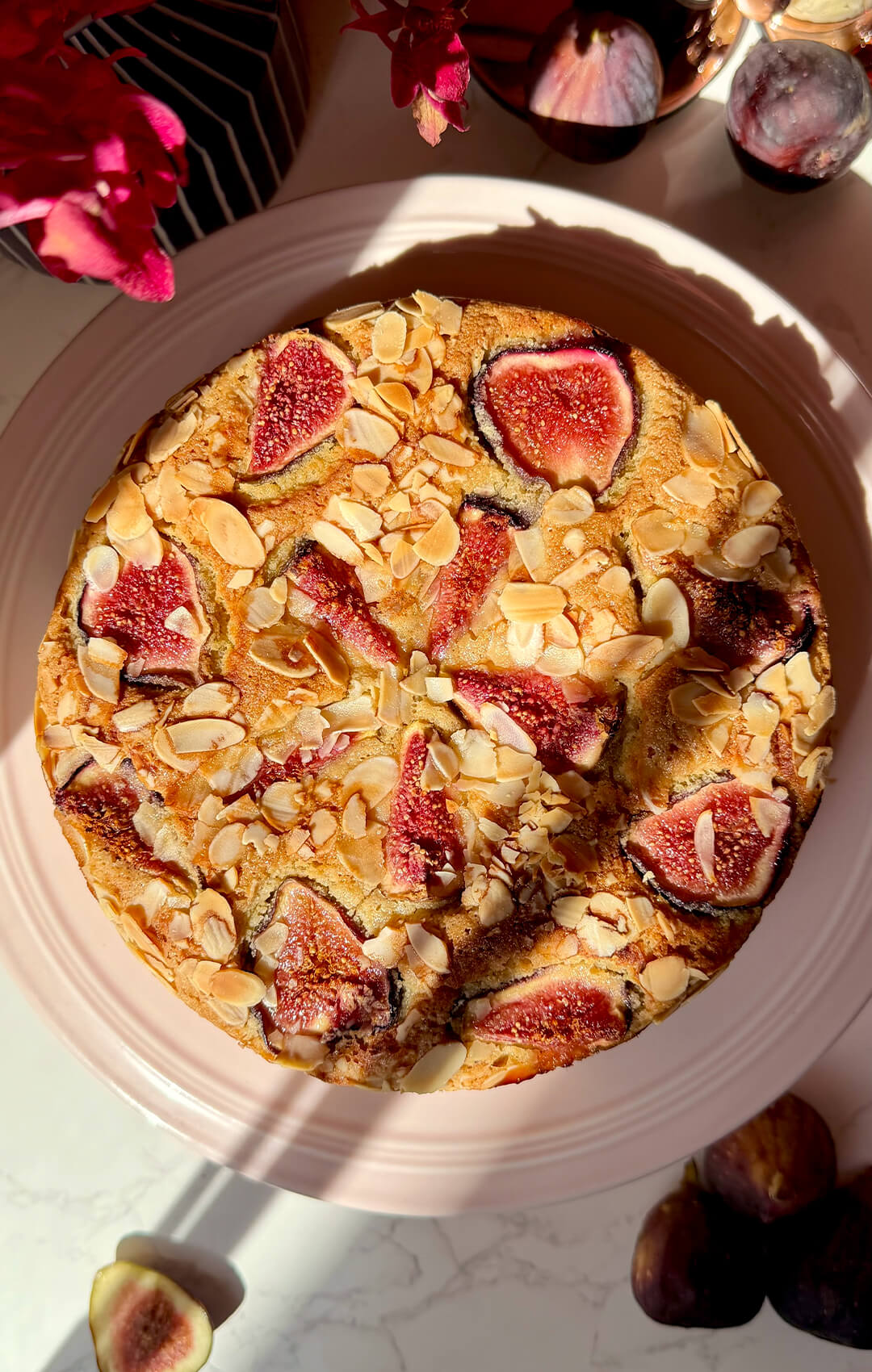 Whole Fig Almond Olive Oil Cake photographed from above in warm sunlight, topped with juicy fresh figs and golden sliced almonds. A healthy, guilt-free, gluten-free, keto-friendly and dairy-free cake made with wholesome ingredients, almond flour, olive oil and a soft, moist crumb.