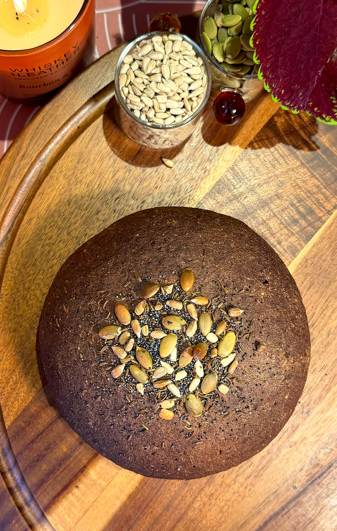 Rustic brown lentil bread with a golden seeded crust on a wooden board, topped with pumpkin seeds, sunflower seeds, sesame seeds, poppy seeds, and caraway. This gluten-free, flourless bread is yeast-free, egg-free, high in fibre, protein-rich, easy to make at home, and has a delicious dark rye-style flavour and look without tasting like lentils.