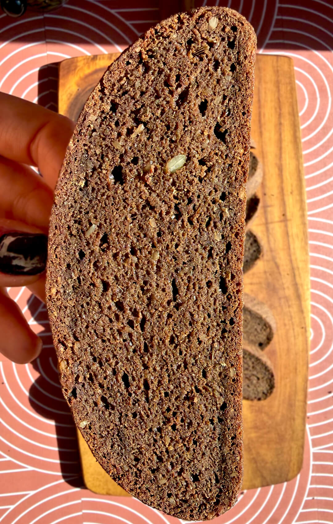 Close-up of a slice of rustic brown lentil bread showing a soft chewy crumb, small air pockets, and hearty seeded texture. This gluten-free, flourless lentil bread is yeast-free, egg-free, high in fibre, protein-rich, satisfying, and tastes like real dark rye-style bread without tasting like lentils.