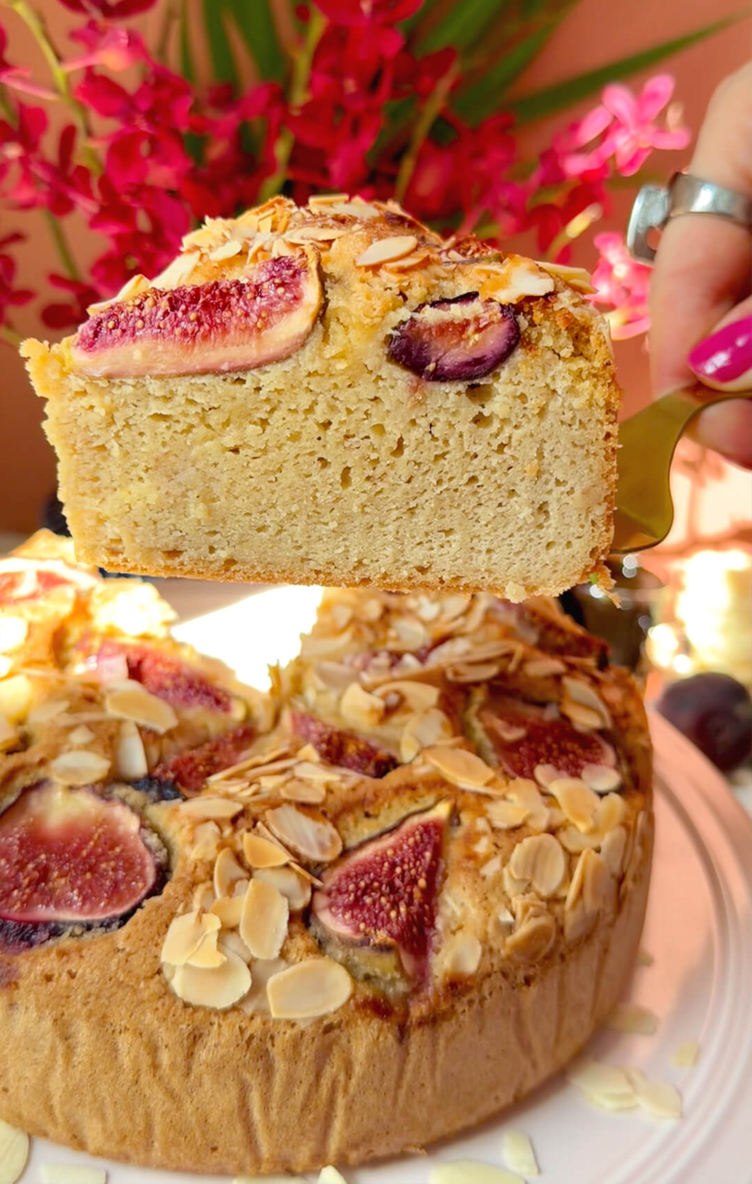 A thick slice lifted from a Fig Almond Olive Oil Cake, showing the tall soft crumb, fresh fig topping and golden sliced almonds. A healthy, guilt-free, gluten-free and keto-friendly cake made with almond flour, olive oil and wholesome ingredients for a moist dessert-like texture.
