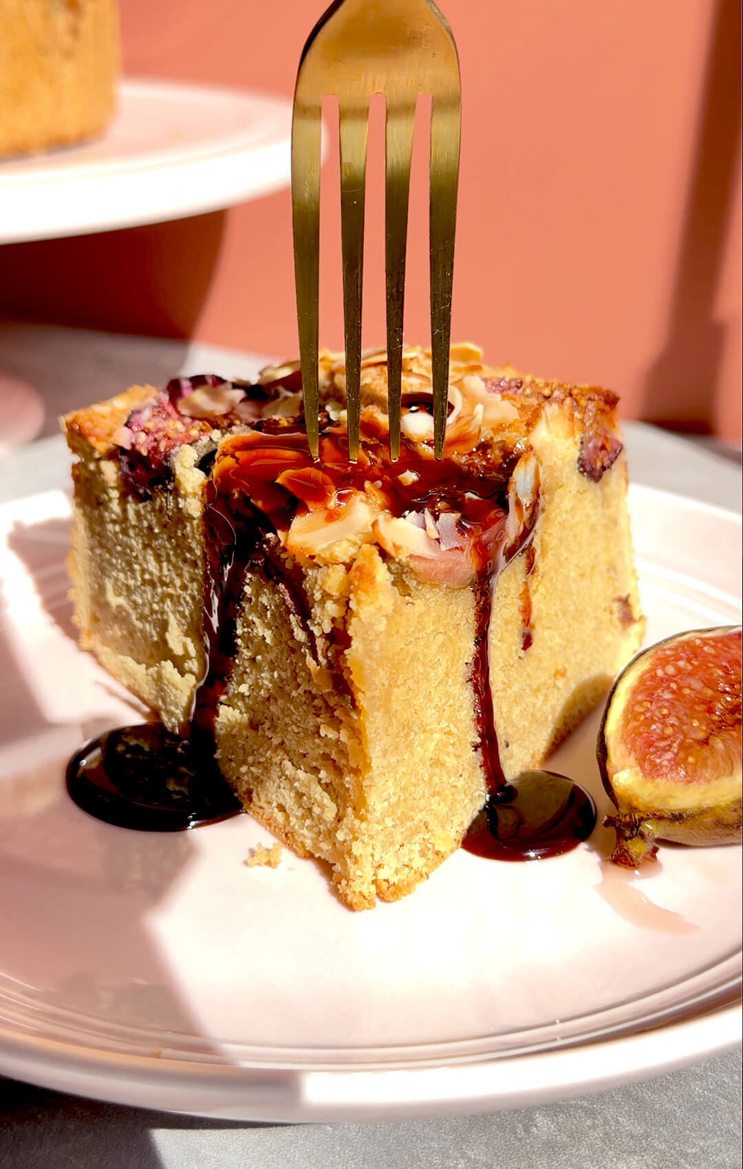 Fork pressing into a slice of Fig Almond Olive Oil Cake with syrup, showing the moist almond flour crumb, roasted figs and golden almond topping. A healthy sugar-free, gluten-free and dairy-free cake made with wholesome ingredients for a soft, luscious dessert texture.