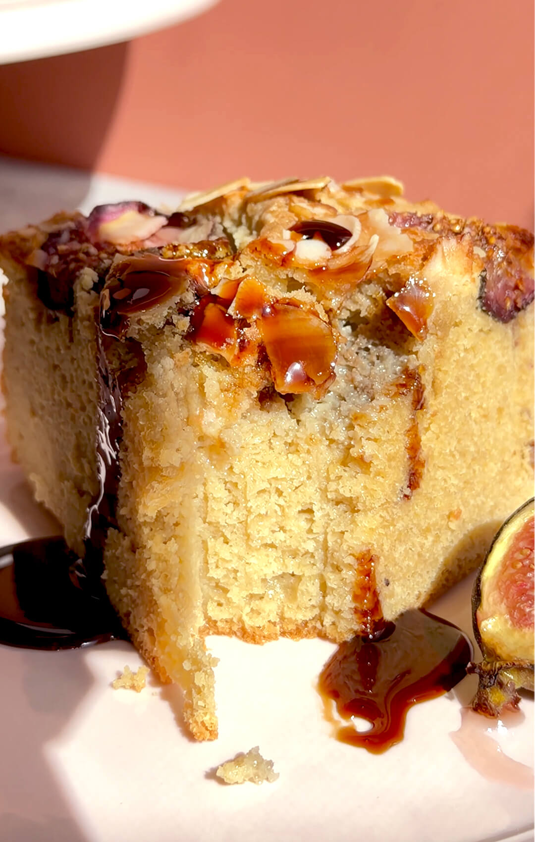 Close-up texture photo of Fig Almond Olive Oil Cake with syrup dripping over a soft, moist almond flour crumb, roasted figs and sliced almonds. This healthy, guilt-free, gluten-free and keto-friendly cake is made with wholesome ingredients and has a rich but balanced dessert feel.