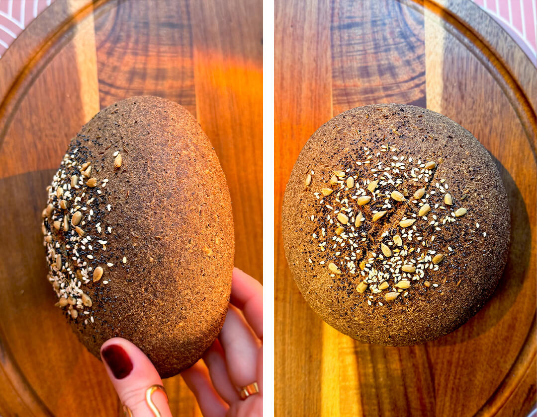Close-up of rustic brown lentil bread with a golden dark rye-style crust and seeded top, held in hand to show its artisan-style shape. This healthy homemade bread is gluten-free, flourless lentil bread is yeast-free, egg-free, high in fibre, protein-rich, satisfying, and has a real bread-like dark rye flavour and look without tasting like lentils and so easy to make at home.