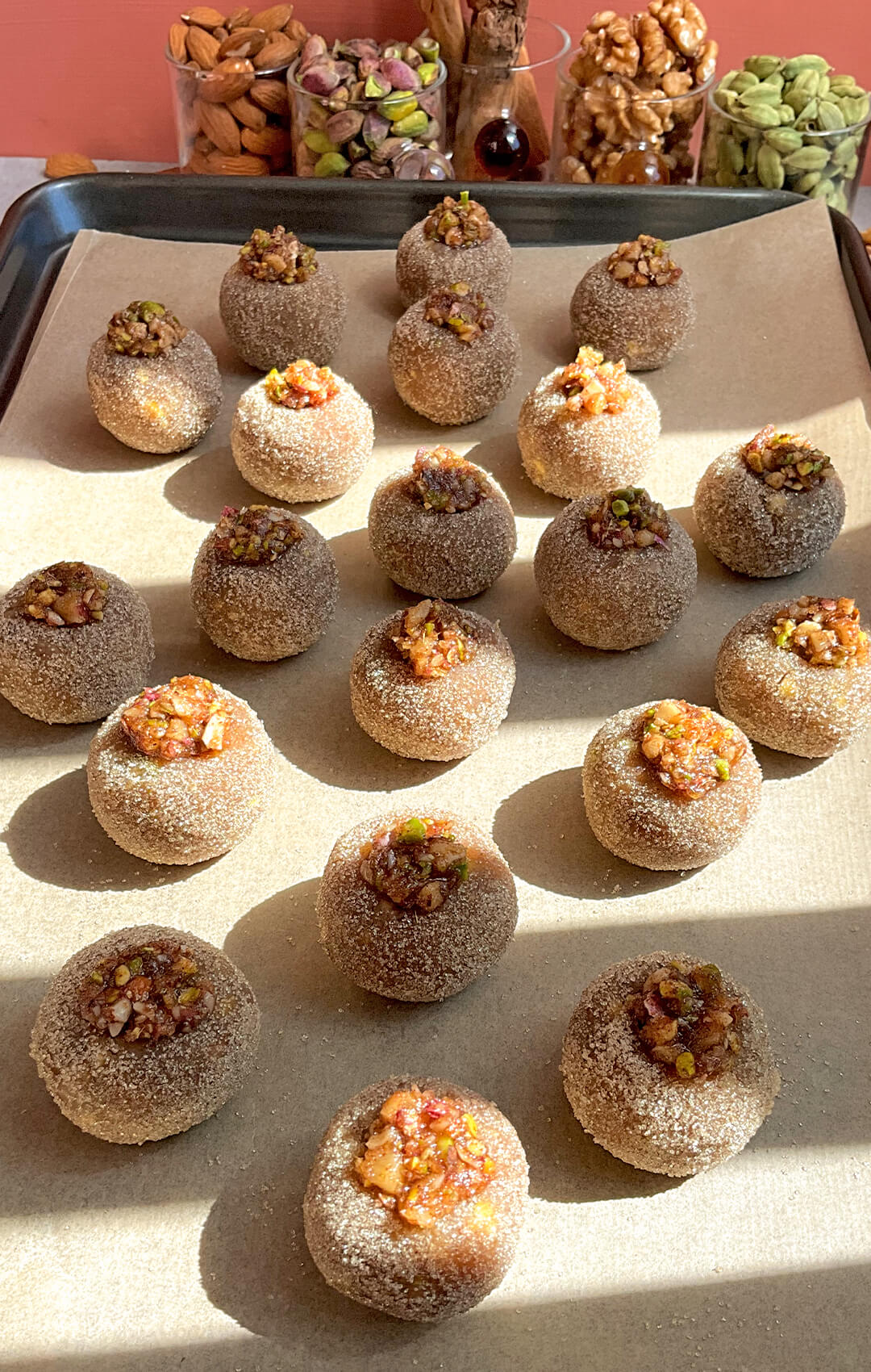 Healthy Baklava Bites arranged on a baking tray before baking, coated in golden monk fruit sweetener and filled with pistachio walnut topping. These easy gluten-free, grain-free, dairy-free and refined sugar-free baklava bites are made without filo pastry, naturally sweetened with honey, filled with almonds, walnuts, pistachios, rose water and warm spices, and bake into a crisp outside with a soft moist centre.