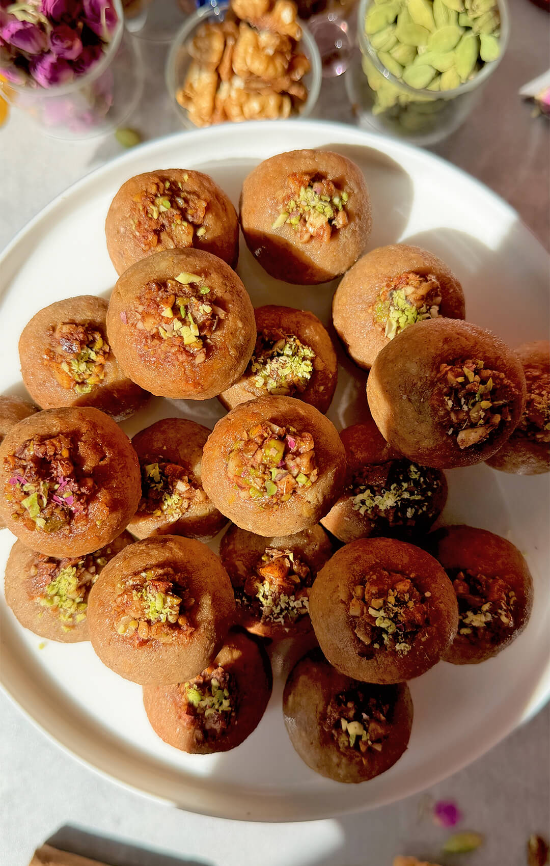 Close-up of Healthy Baklava Bites topped with pistachio walnut filling, with one bite held above the plate to show the golden, fragrant, nutty texture. These paleo, gluten-free, grain-free, dairy-free and refined sugar-free baklava bites are naturally sweetened with honey, made with almonds, walnuts, pistachios, rose water and warm spices, crisp outside, moist inside, and perfect for an easy healthy dessert or sweet snack.