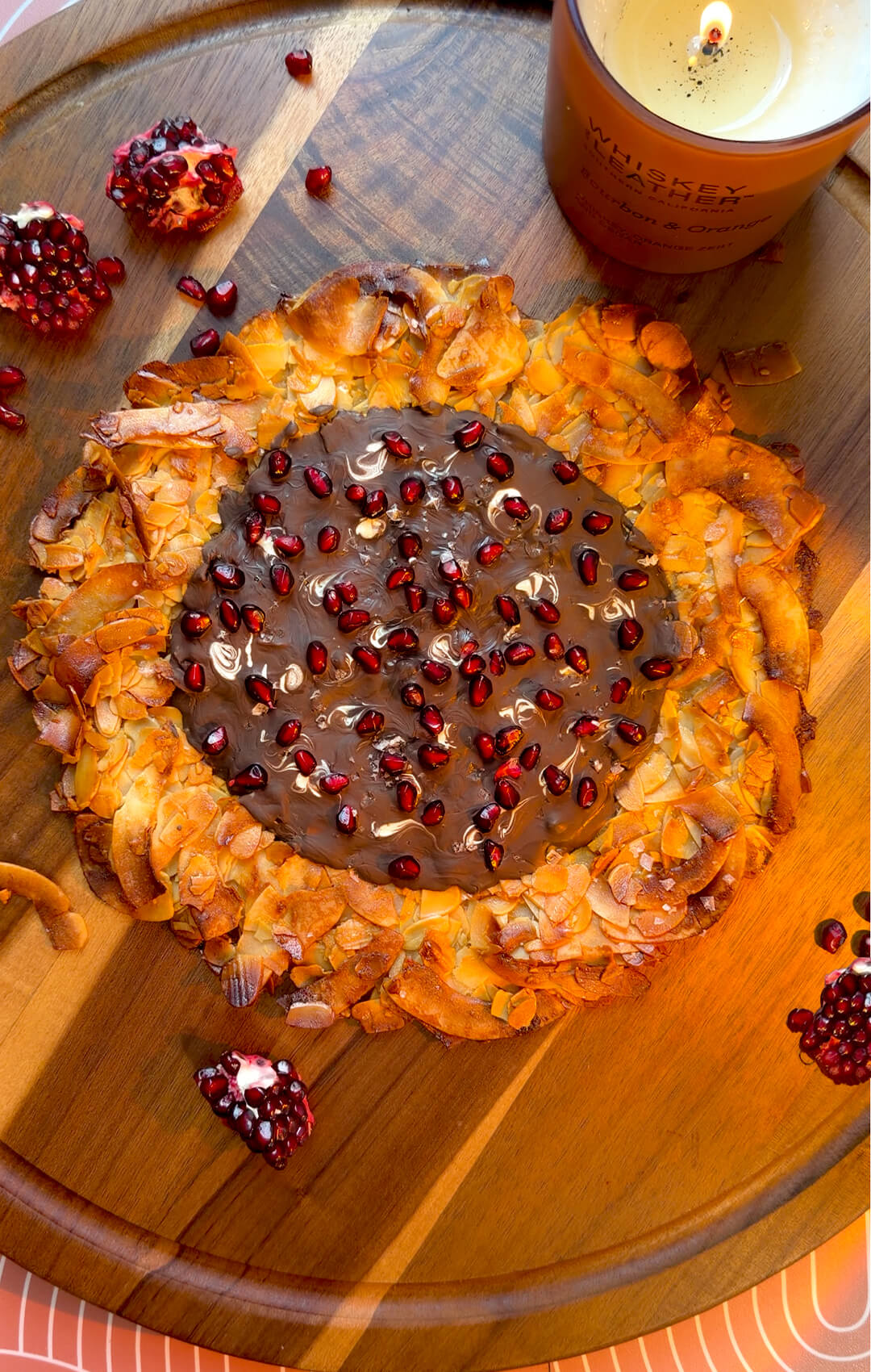 Quick and easy crunchy Florentine cookie pizza made at home with toasted almond slices and coconut flakes, featuring a golden crisp texture with a soft chewy centre, coated in dark chocolate and fresh pomegranate arils (seeds). This healthy recipe is gluten-free, paleo, and refined sugar-free.