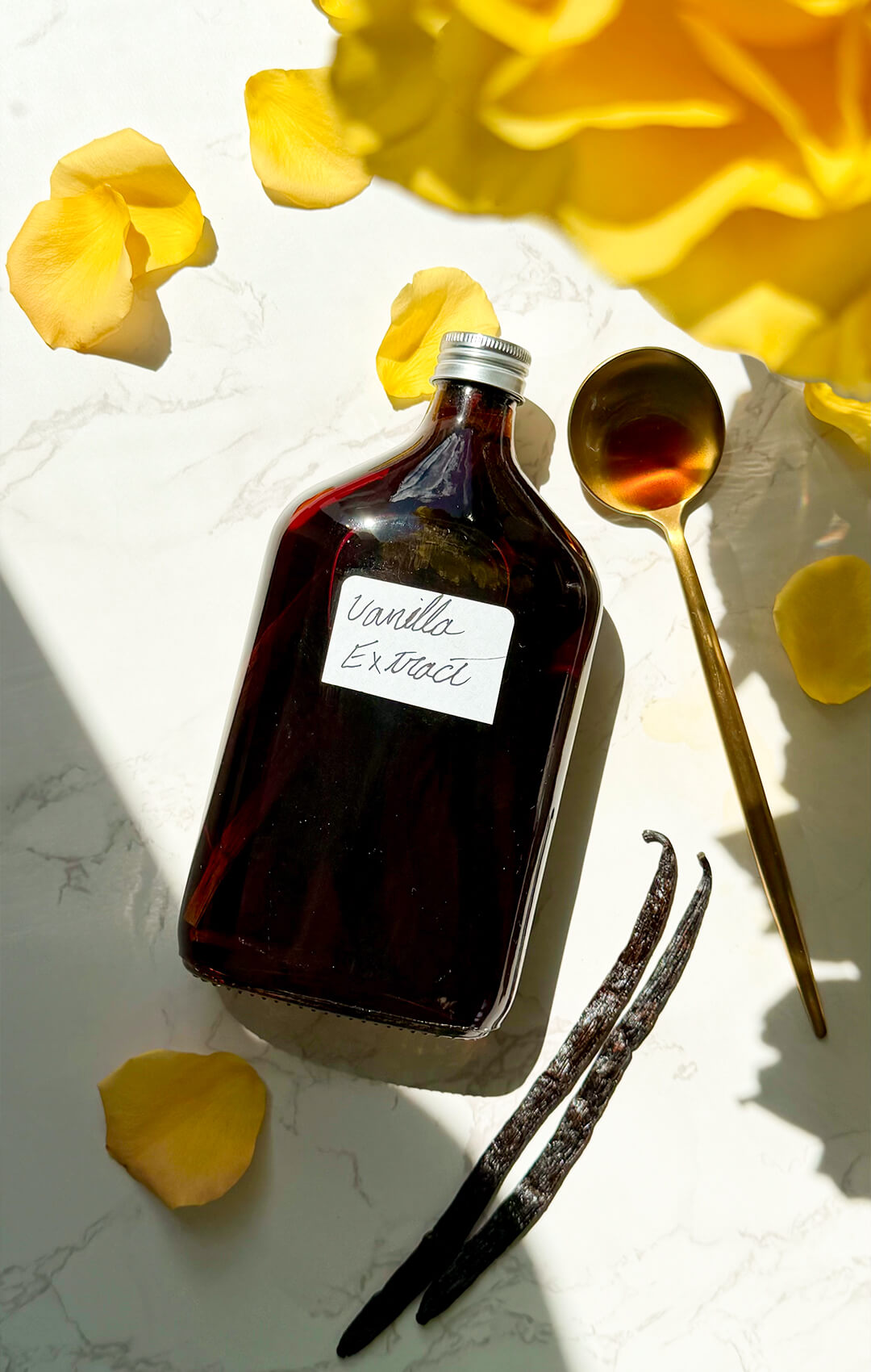 © Healthy Food by Annie. All rights reserved. No reuse, copying, editing, reposting, or redistribution without written permission. A close food styling image of homemade vanilla extract in a gold spoon beside the bottle, showing the deep amber colour and rich vanilla infusion. It takes less than 10 minutes to prepare, with only 2-ingridinat.