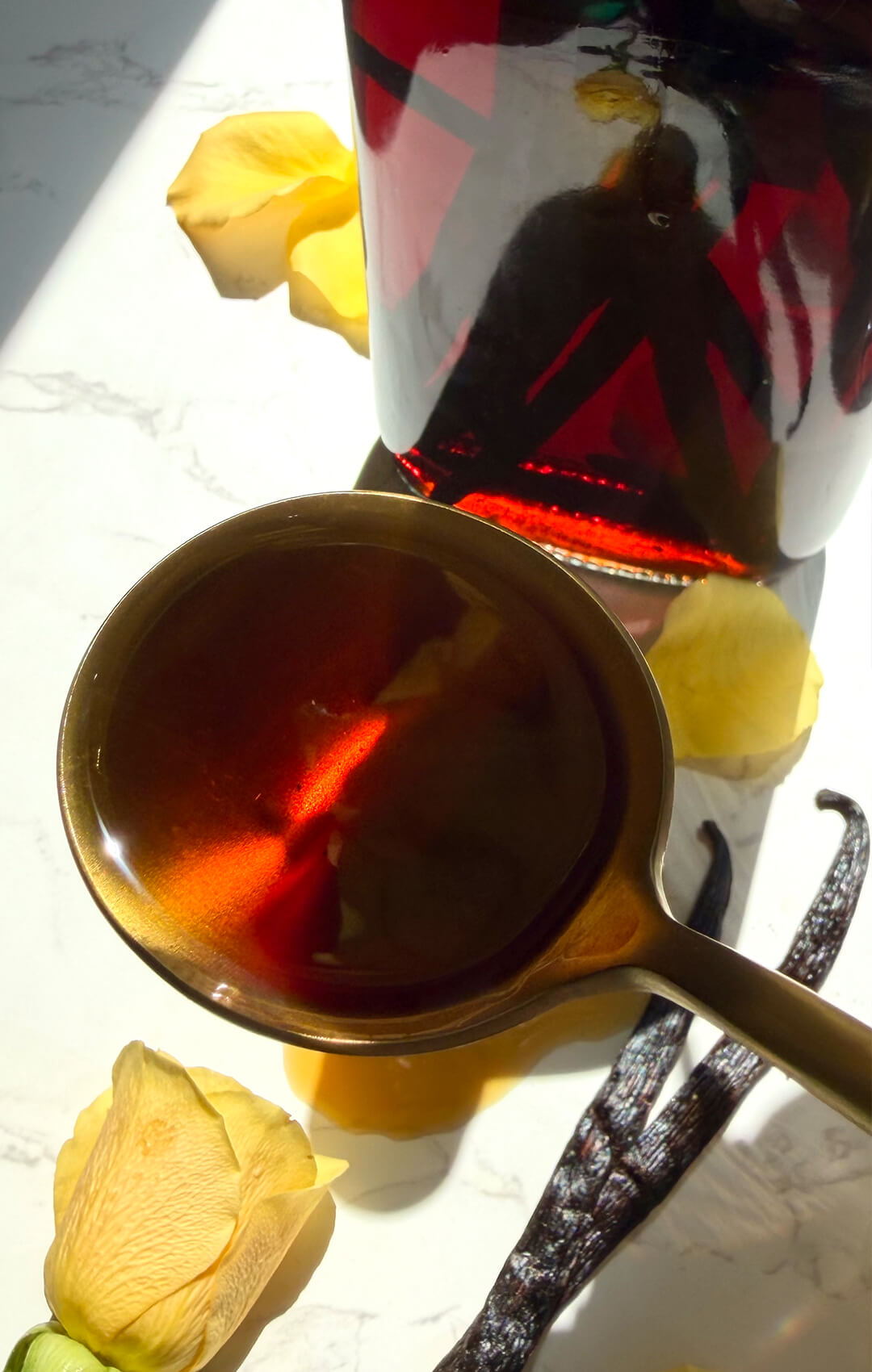 Dark homemade vanilla extract close up with a spoon of amber vanilla and Madagascar beans in the bottle, showing a strong pure vanilla extract for baking. easy recipe.
