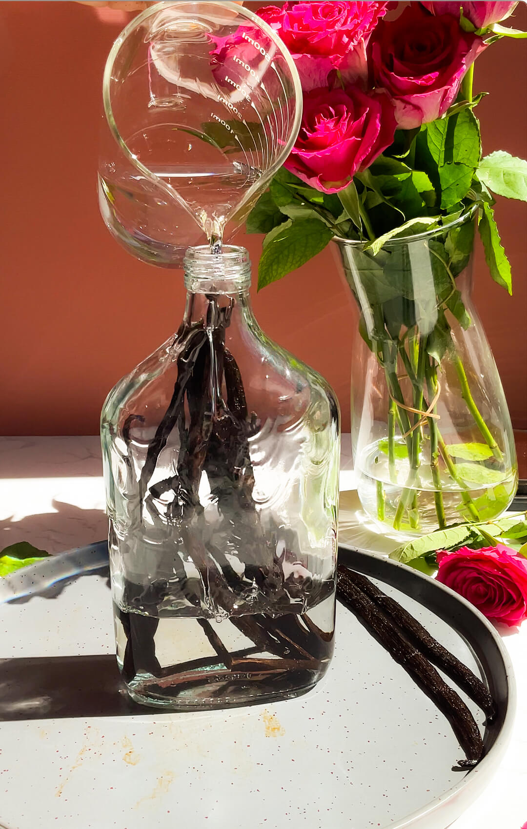 © Healthy Food by Annie. All rights reserved. No reuse, copying, editing, reposting, or redistribution without written permission. Vodka being poured into a glass bottle filled with Madagascar vanilla beans to make homemade vanilla extract with two simple ingredients.