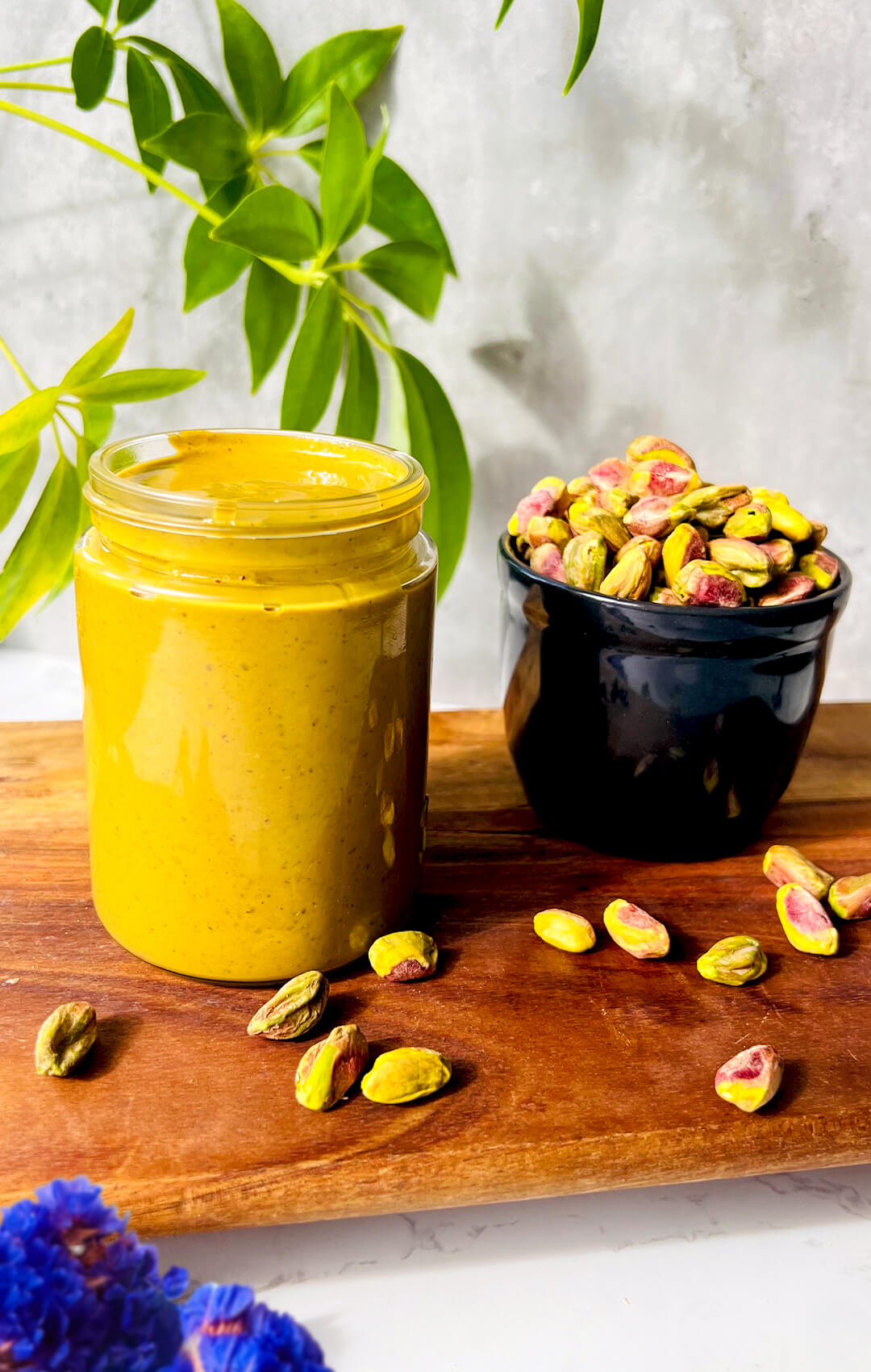 : Jar of homemade pistachio butter next to raw pistachios, showing a smooth creamy spread made from one real ingredient, perfect for healthy baking, desserts, and spreading.