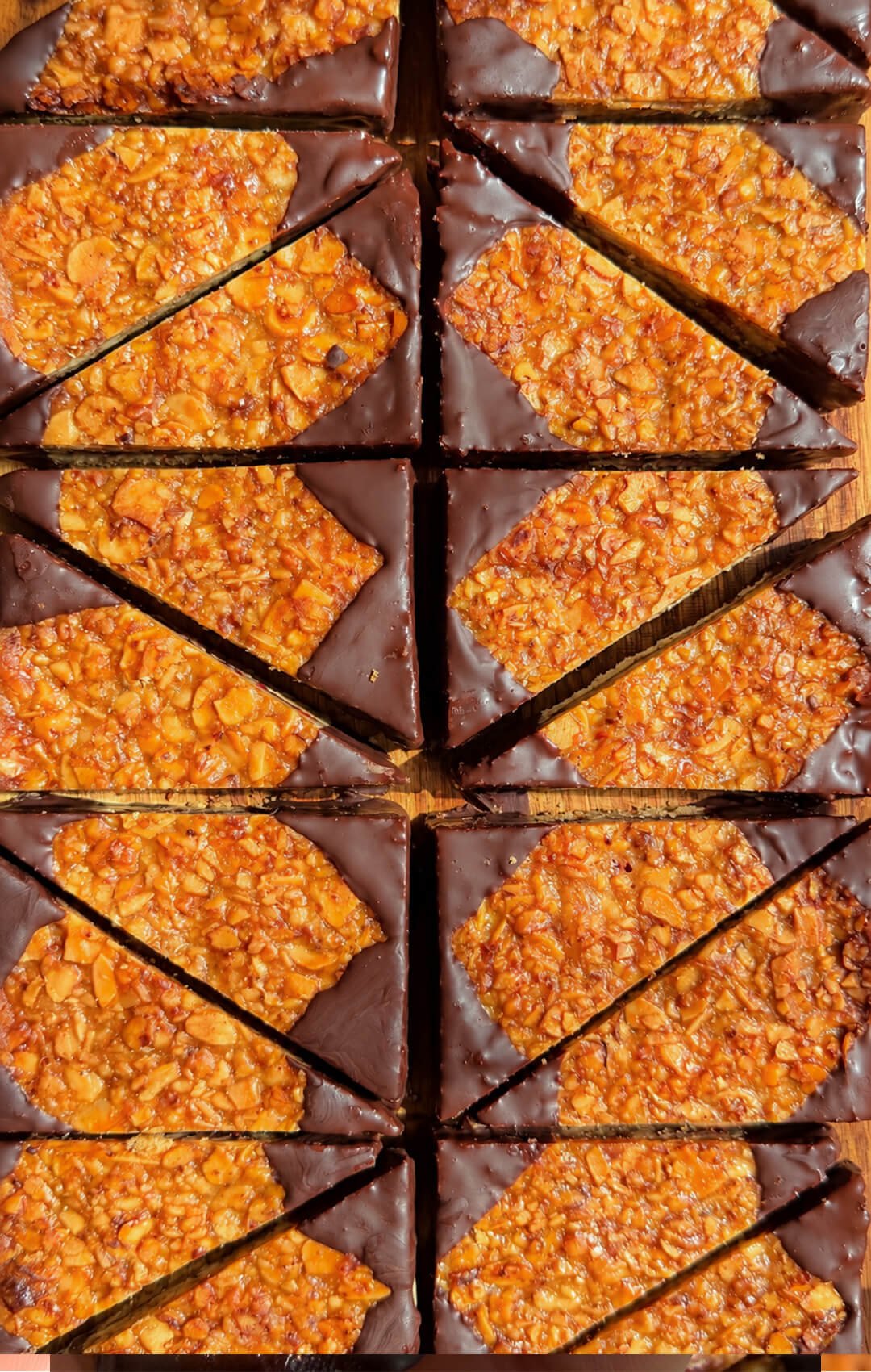 Tray of Almond Jam Crunch Cookie Corners with caramelized almonds and walnuts, raspberry jam and dark chocolate dipped corners.